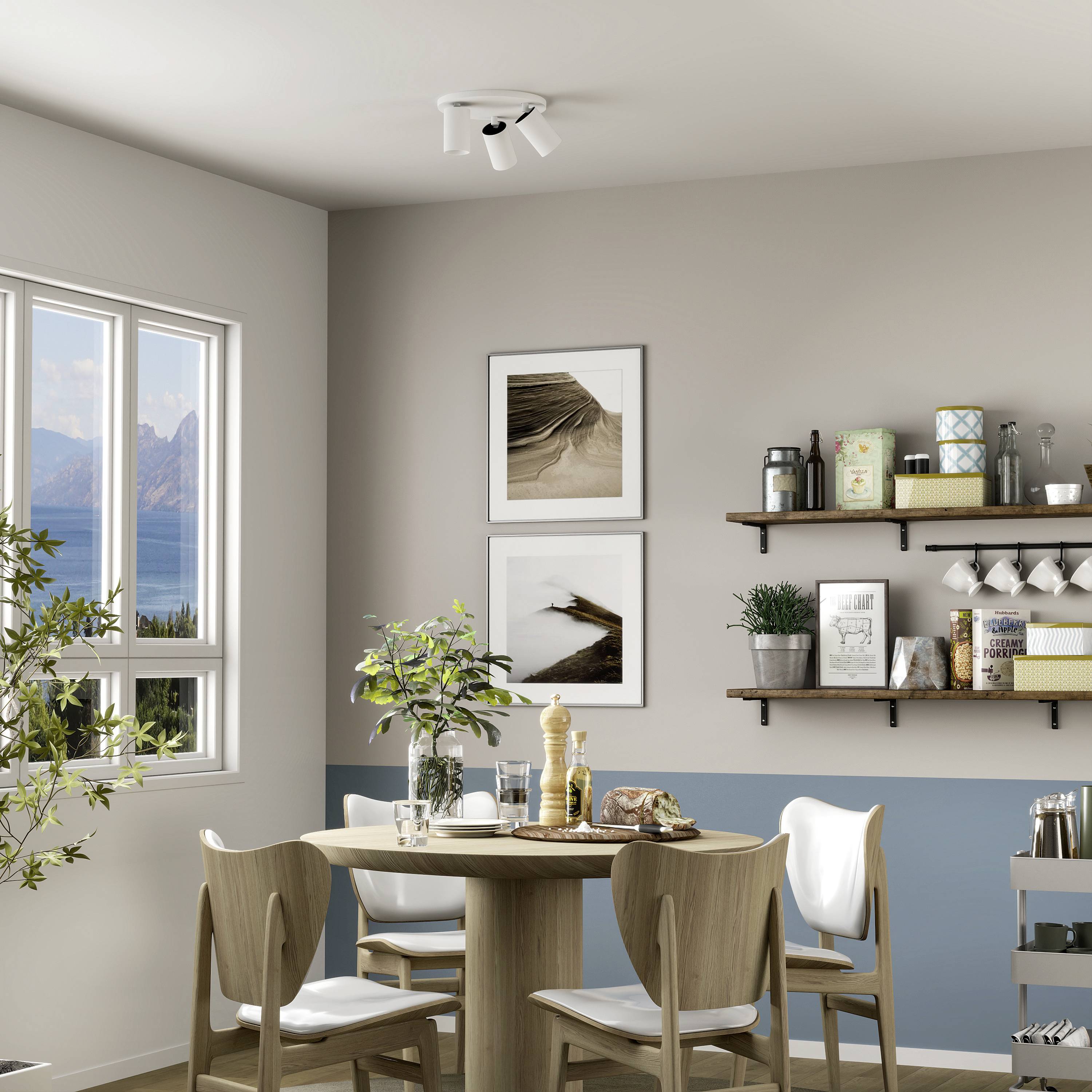 Jedáleň s okrúhlym stolom a štyrmi stoličkami. Na stenách visia zarámované obrazy a police s dekoratívnymi predmetmi. Okno s výhľadom na jazero.