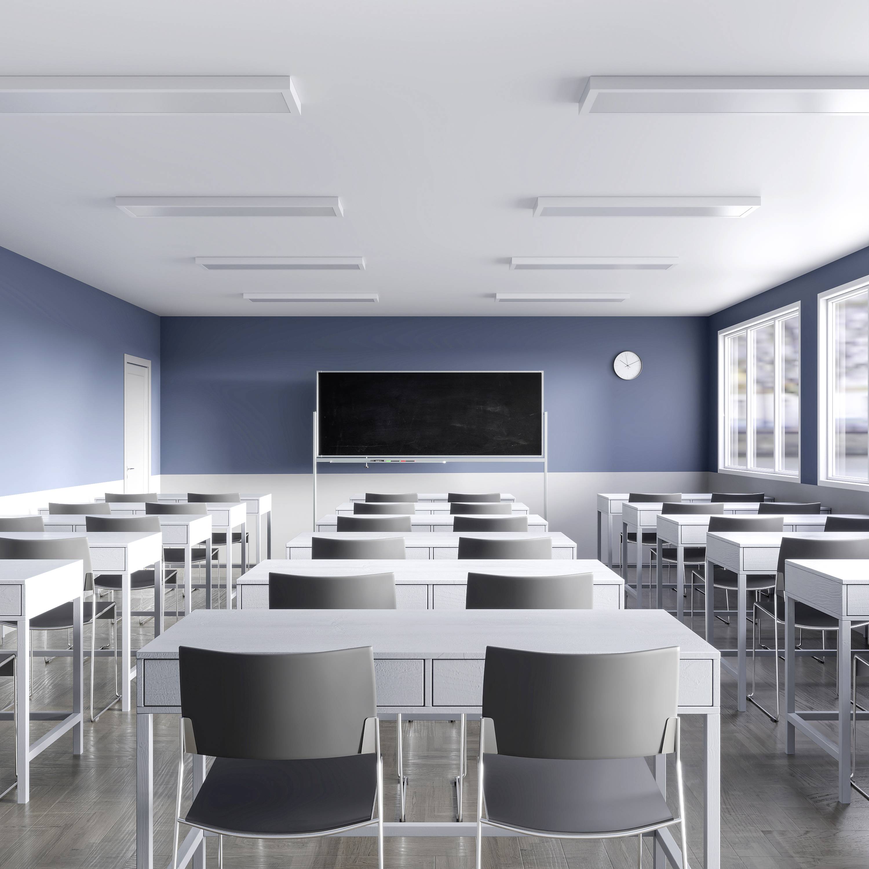 Prázdna, moderná učebňa s modrými stenami a veľkým oknom. Nachádza sa tu niekoľko stolov a stoličiek, whiteboard a hodiny.