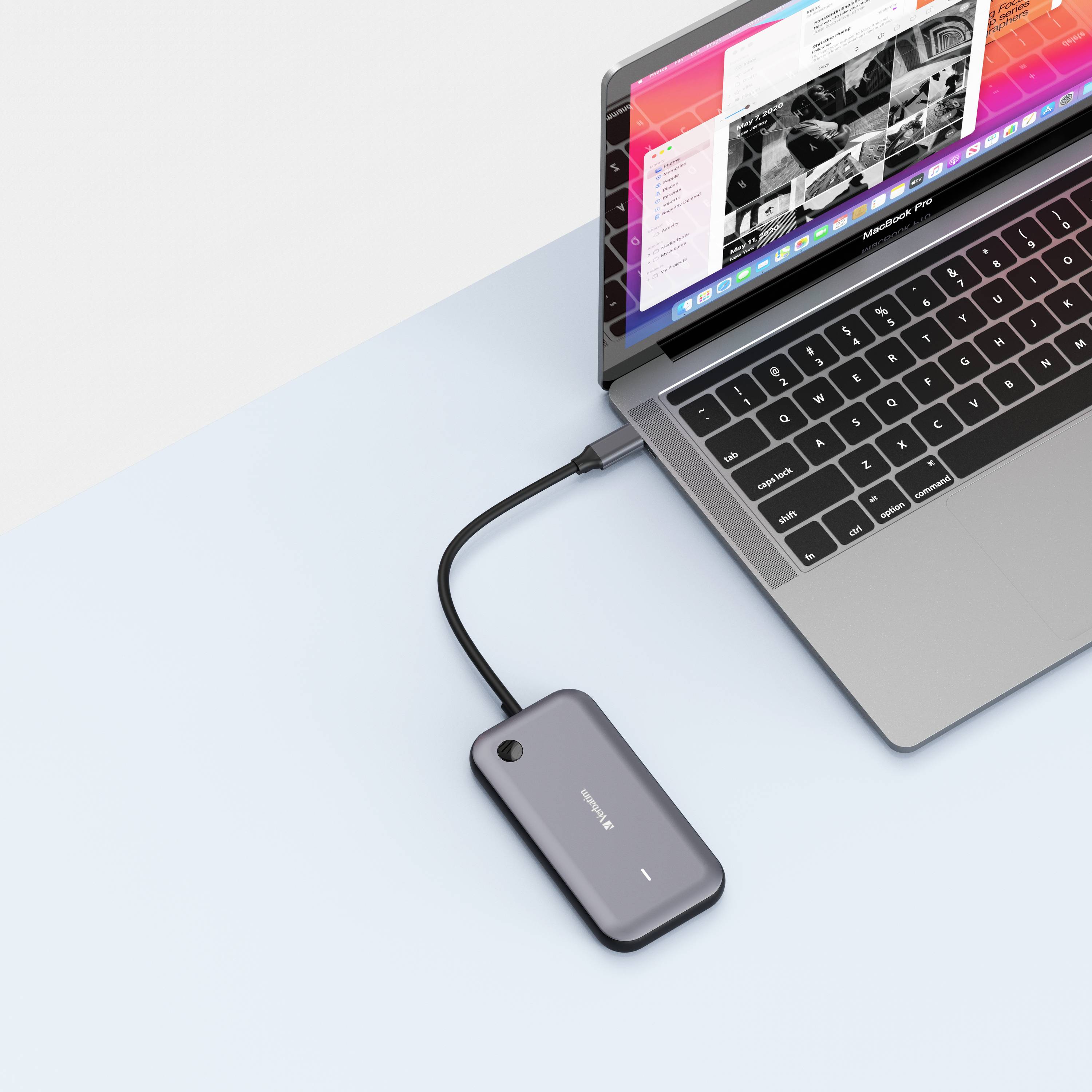 Laptop s otvorenou obrazovkou zobrazuje aplikácie a priečinky. Externá jednotka je pripojená prostredníctvom kábla.