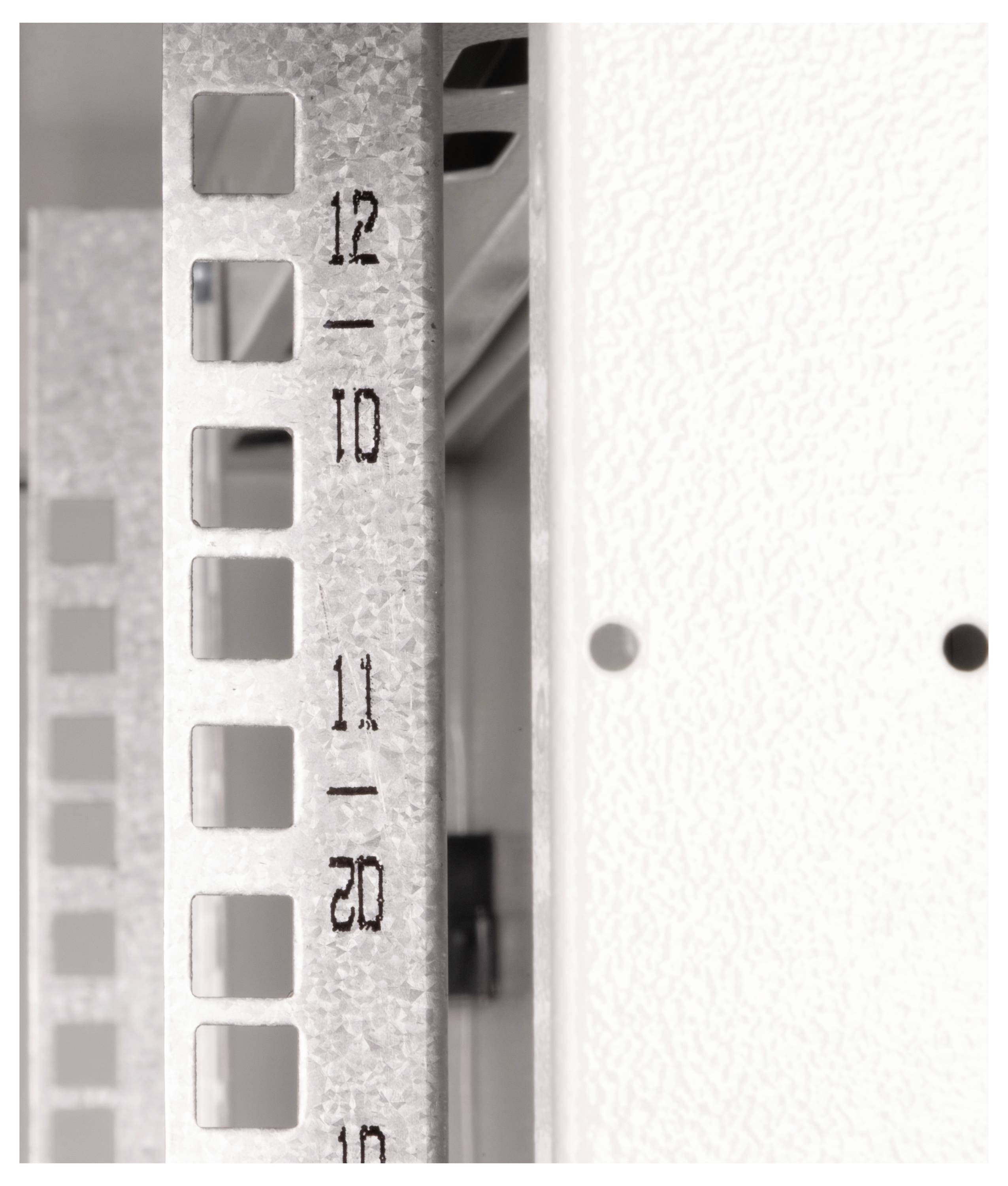 Detailný záber kovového rámu s očíslovanými otvormi, pravdepodobne súčasť regálovej konštrukcie, zobrazujúci čísla '10', '11' a '12' vedľa seba.