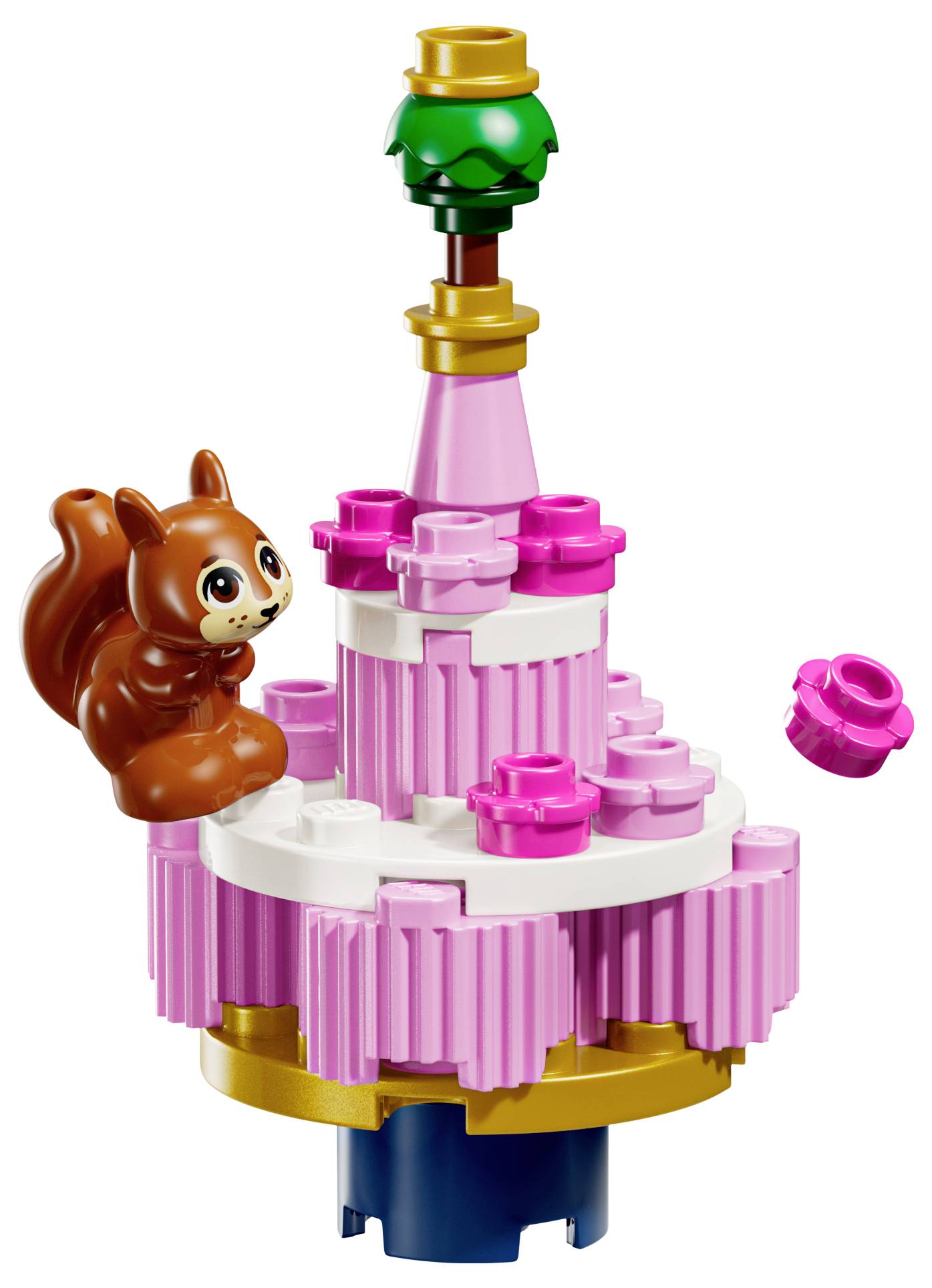 Veverička sedí na farebnej, viacvrstvovej LEGO stavbe pripomínajúcej tortu, ozdobenej ružovými a bielymi kockami a s malou zelenou časťou na vrchu.