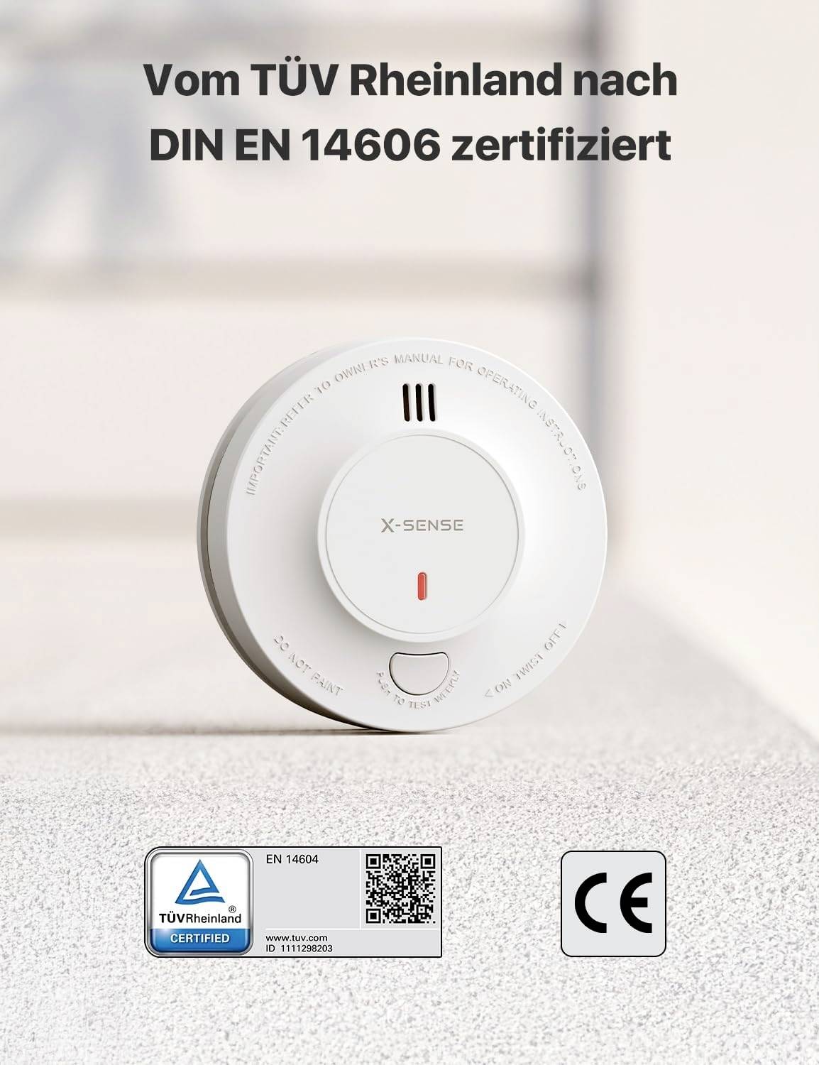 Detektor dymu na stole. Text hore: "Certifikovaný spoločnosťou TÜV Rheinland podľa normy DIN EN 14606". Dole: TÜV, QR kód, symbol CE.