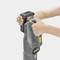 Osoba pripája batériu k šedému čistiacemu zariadeniu Kärcher. Ruky nastavujú batériu v hornej časti zariadenia.