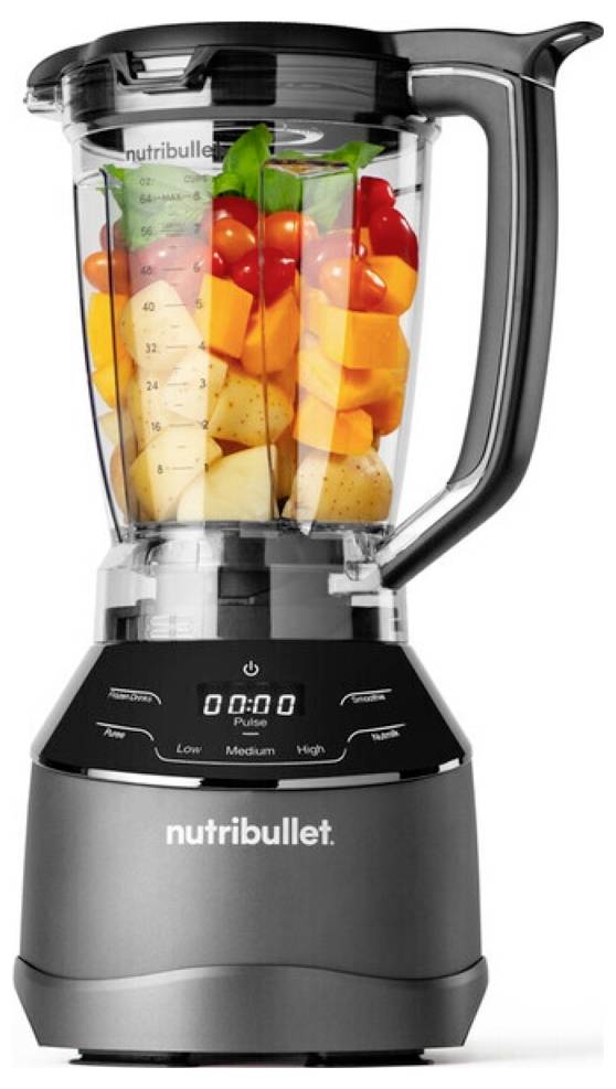 Vysoký tmavosivý mixér Nutribullet naplnený rôznorodým ovocím a zeleninou, vrátane cherry paradajok, mrkvy a pomarančových plátkov.