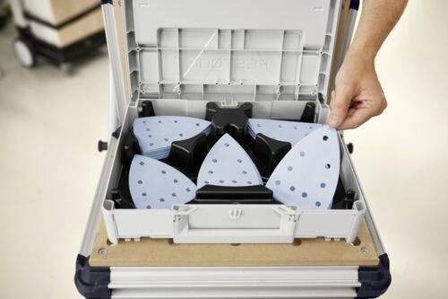 Ruka vkladá modrý trojuholníkový podložkový prvok s otvormi do púzdra na nástroje, kde sú podobné podložky usporiadané okolo centrálneho bodu.