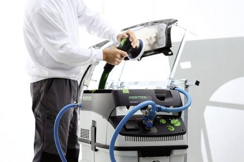 Osoba používa leštiaci nástroj pripojený k miniaturnej odsávacej jednotke Festool CTL v pravdepodobnom prostredí automobilovej dielne.