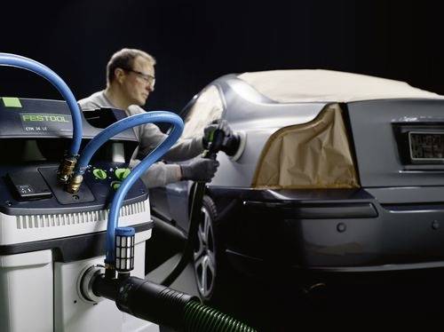Osoba leští auto pomocou nástroja, pričom neďaleko je pripojený stroj Festool, čo naznačuje proces detailného čistenia automobilu.