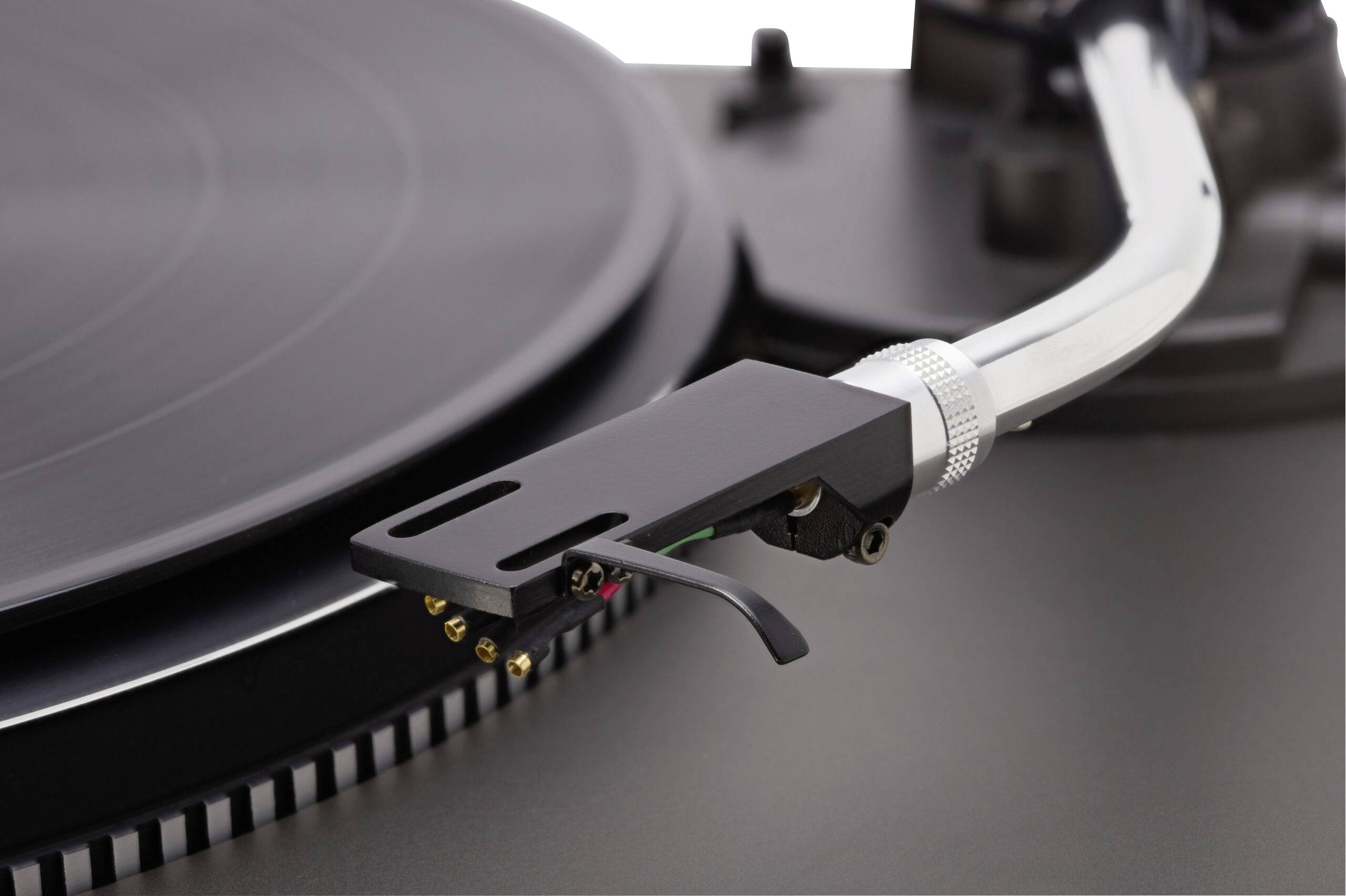 Detailný záber ramena a hrotu gramofónovej ihly umiestnený nad vinylovou platňou na gramofóne.