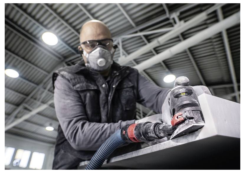 Pracovník v ochrannom oblečení brúsi povrch vo vnútri, pričom sa sústreďuje na bezpečnosť a presnosť.