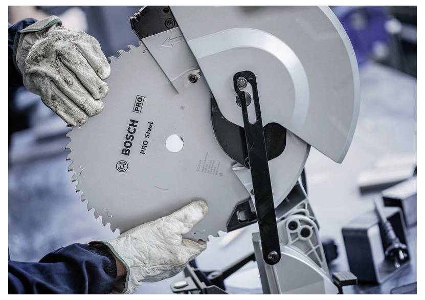 Ruky v ochranných rukaviciach vkladajú pílový kotúč Bosch Pro Steel do elektrickej píly, čo naznačuje použitie nástroja a bezpečnostné vybavenie.