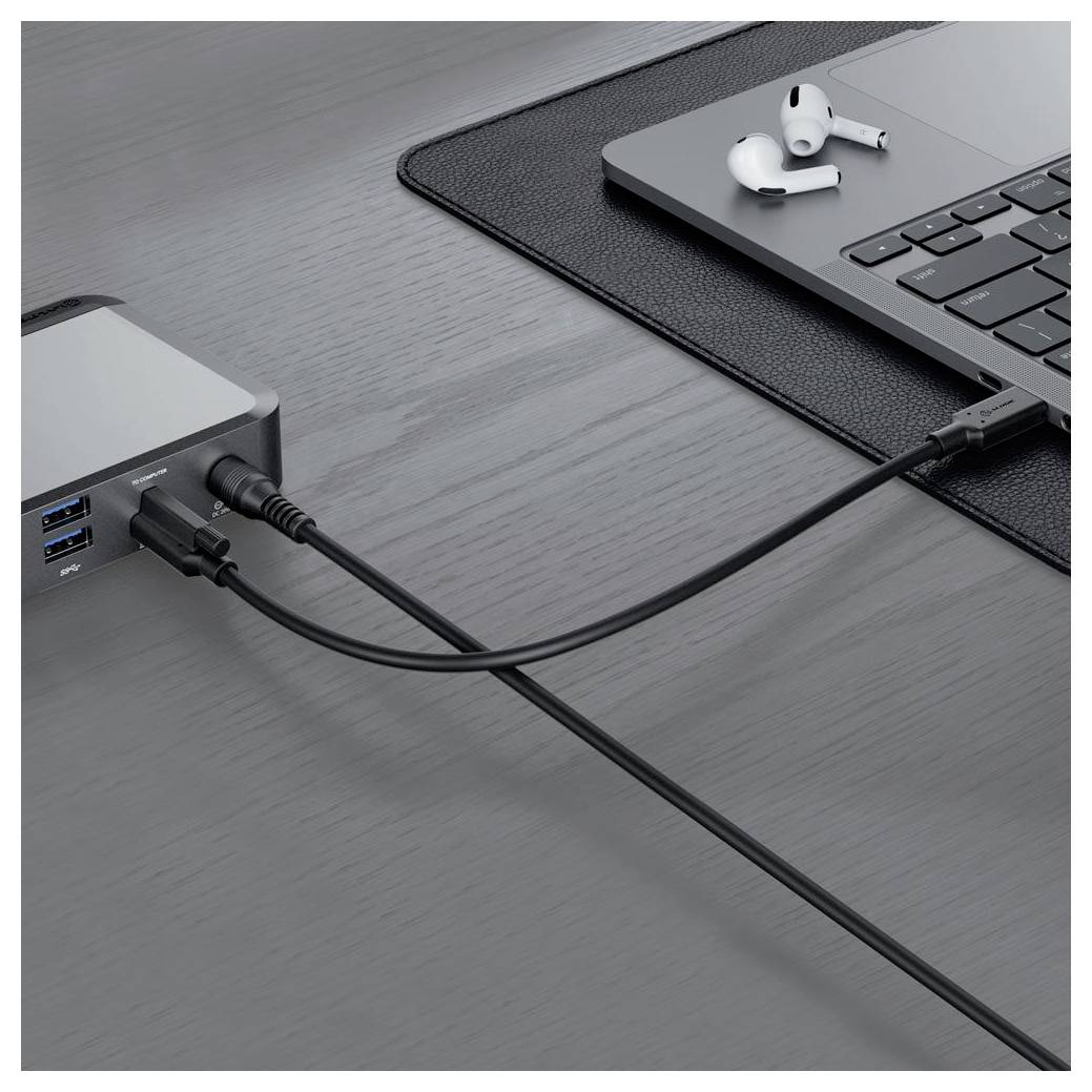 Laptop na stole je pripojený k multiportovému USB rozbočovaču pomocou káblov, vedľa ktorého sú umiestnené bezdrôtové slúchadlá do uší.