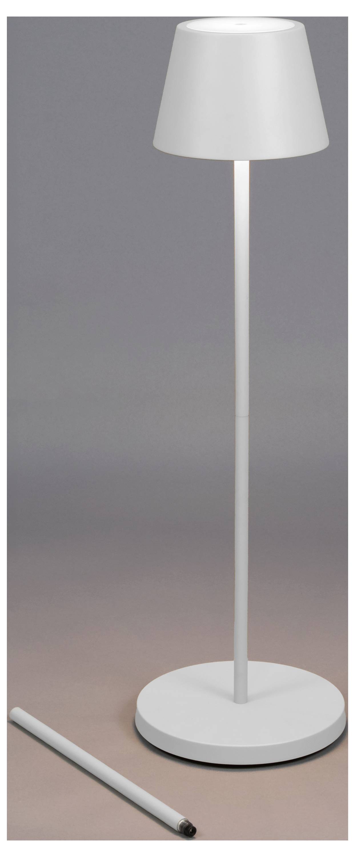 Elegantná, moderná biela stojanová lampa s valcovitou základňou a tienidlom, stojaca kolmo. Valcovitý predmet leží horizontálne pri základni.