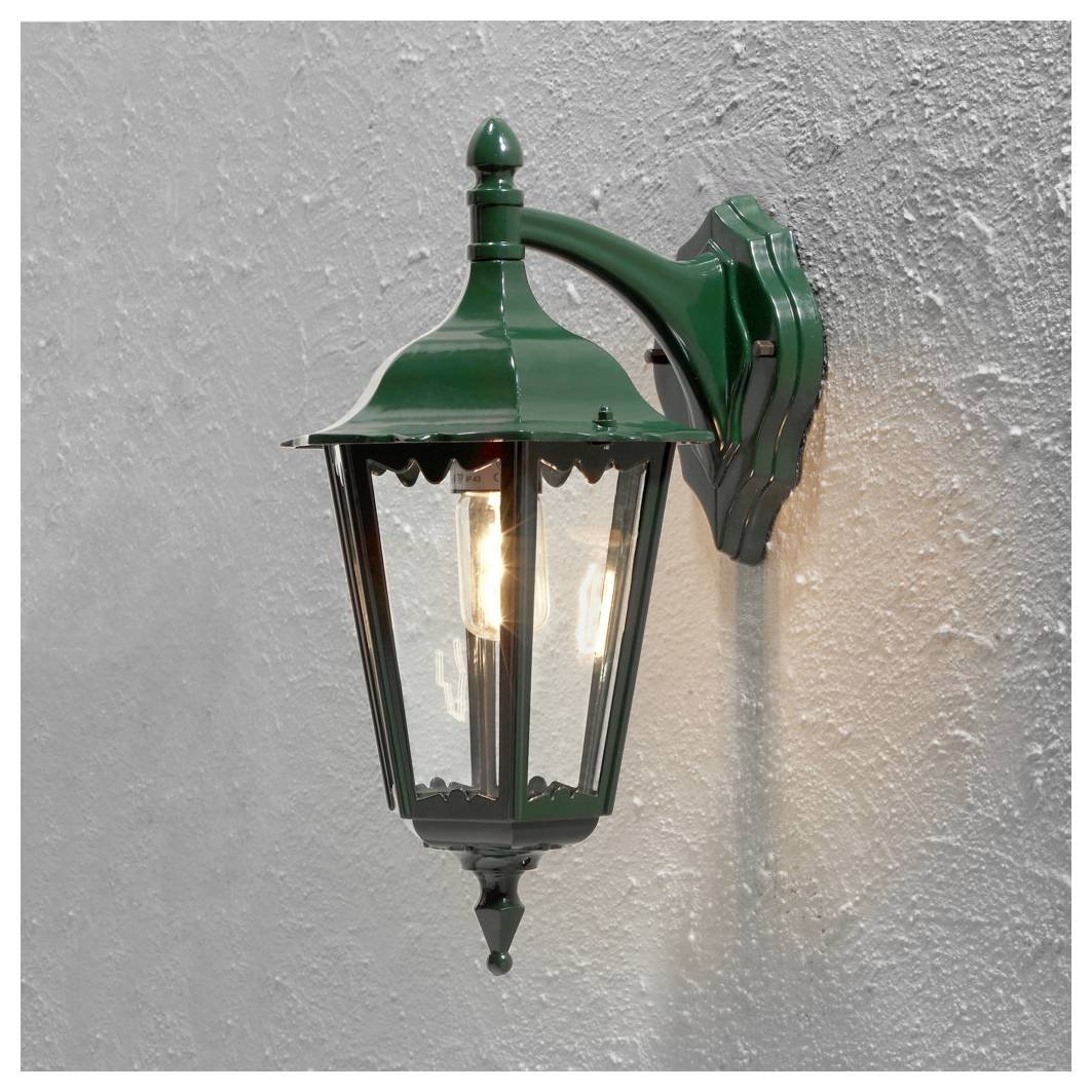 Zelená vintage lampa vonkajšieho štýlu so svietiacimi žiarovkami, pripevnená na textúrovanej, svetlej stene.