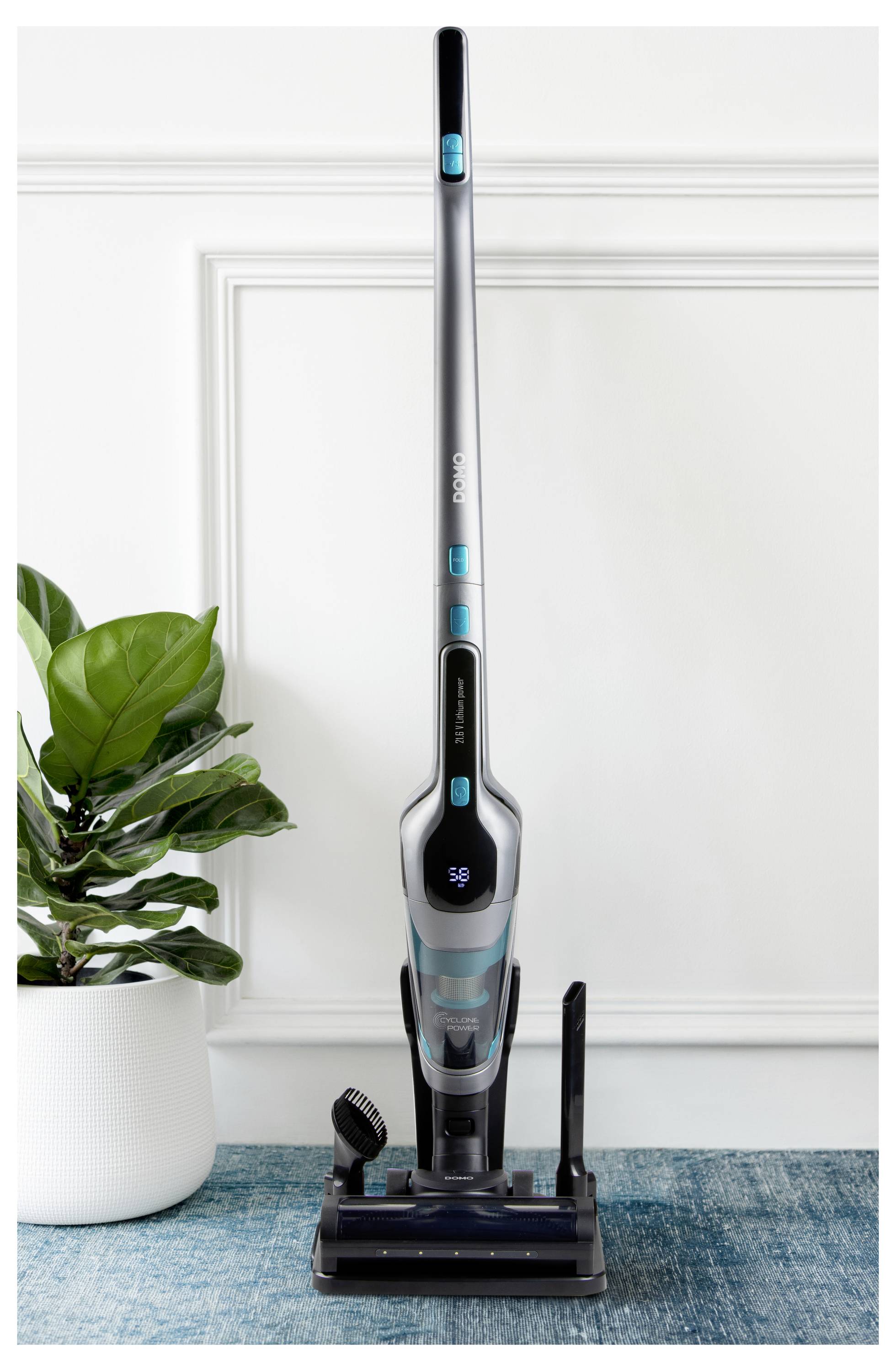 Štíhly vertikálny bezdrôtový vysávač v modernej miestnosti so zelenou rastlinou.