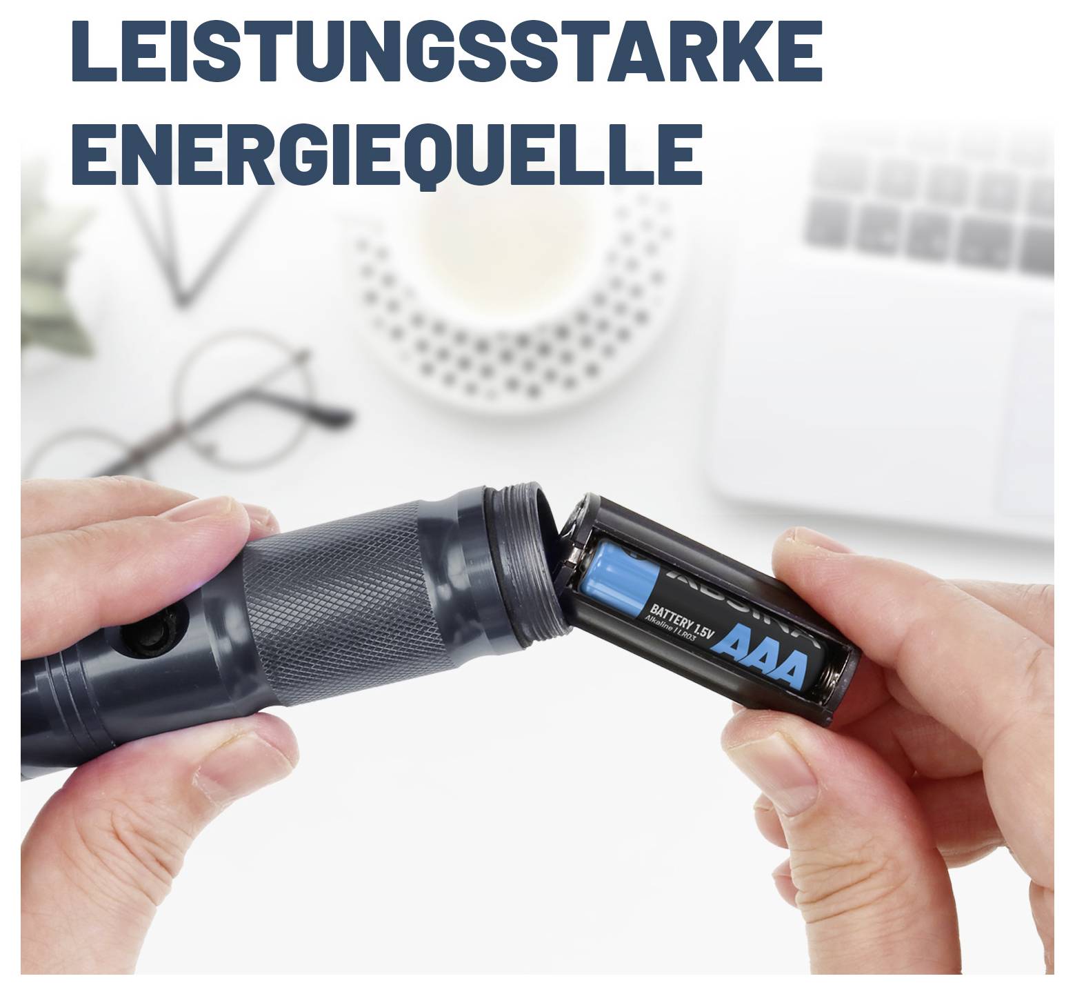Osoba vkladá batérie AAA do svietidla s nemeckým textom „LEISTUNGSSTARKE ENERGIEQUELLE" (Výkonný zdroj energie) nad nimi.