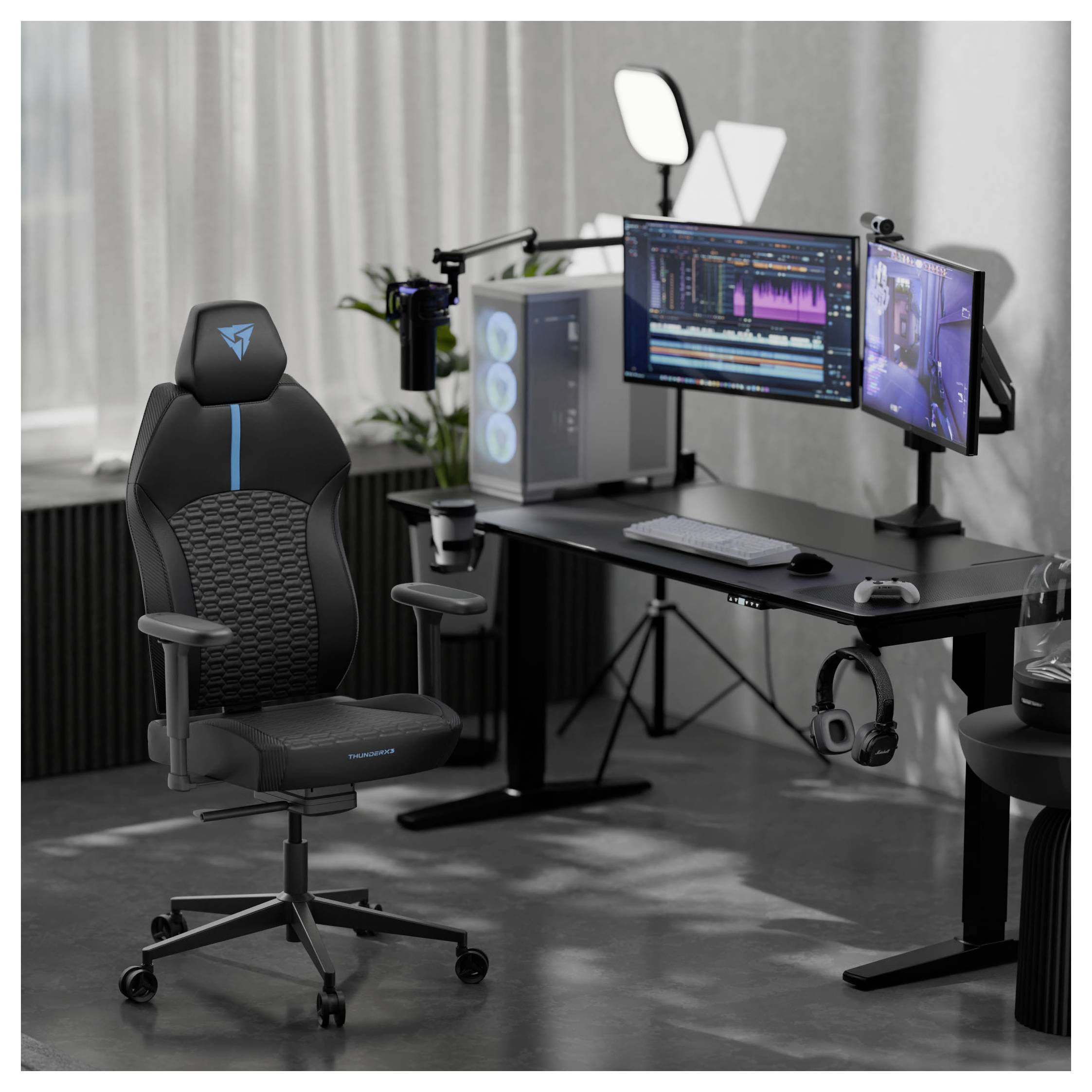 Herná zostava s dvomi monitormi na stole, na ktorých je zobrazený editačný softvér. Na mieste je herná stolička, mikrofón a počítač s RGB podsvietením.