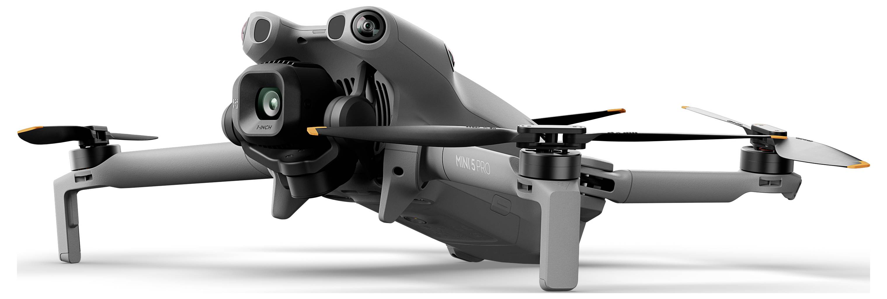 Sivý dron odpočívajúci na pristávacom podvozku, pohľad spredu z ľavej strany, zobrazujúci jeho kameru a vrtuľky.