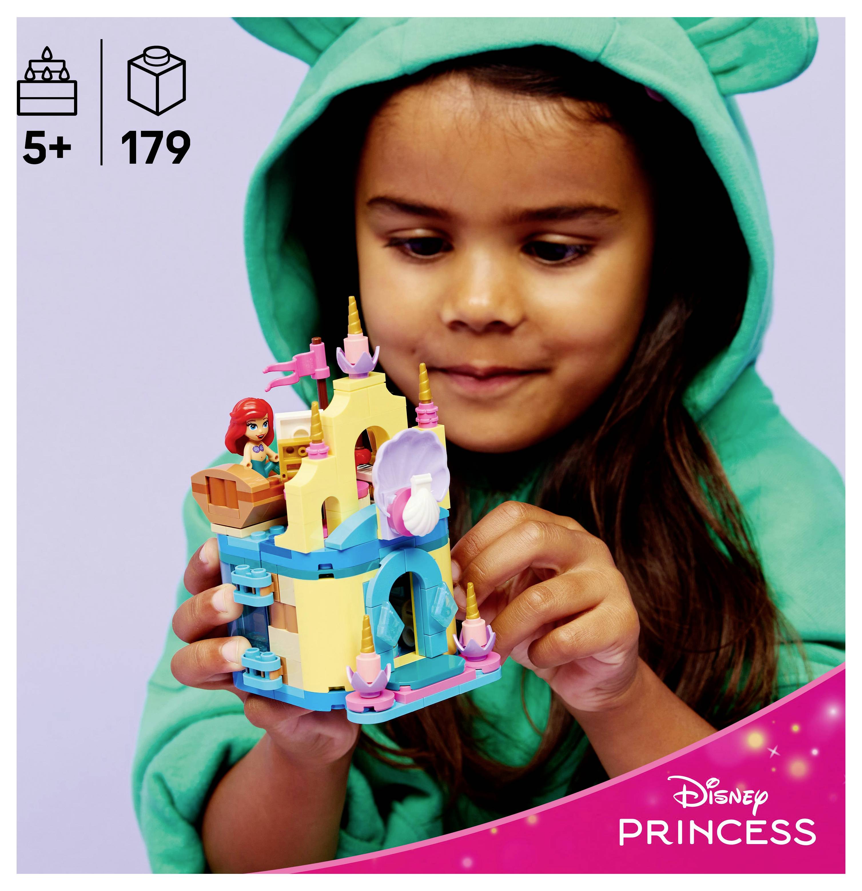 Dieťa v zelenej mikine sa hrá so stavebnicou LEGO Disney Princess, ktorá obsahuje figúrku Ariel a zámok, vhodnou pre deti od 5 rokov, pozostávajúcou z 179 dielikov.