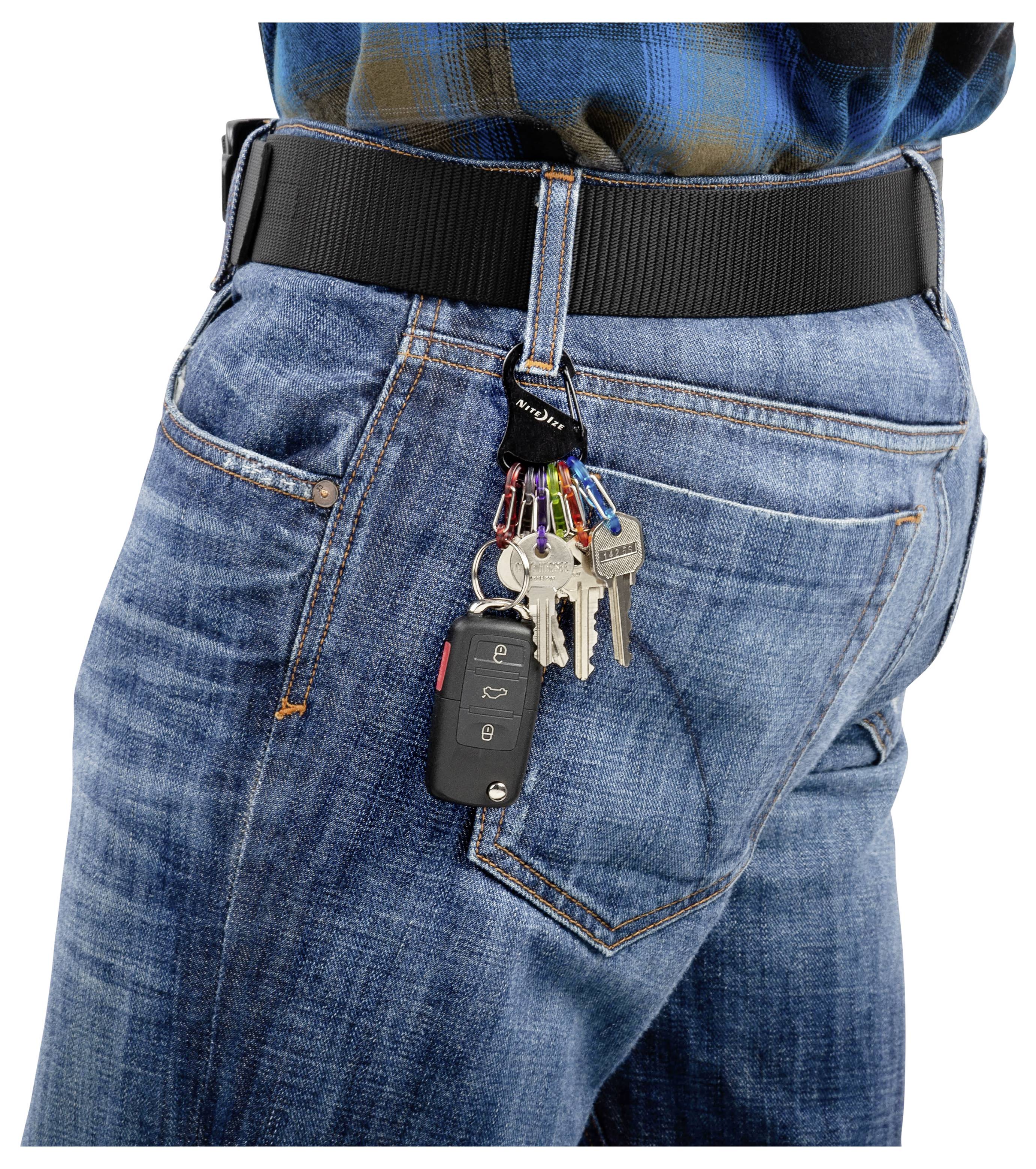 Osoba oblečená v modrých džínsach s čiernym opaskom má sadu kľúčov a autokeľ pripnuté na slučke opasku, visiacich po boku.