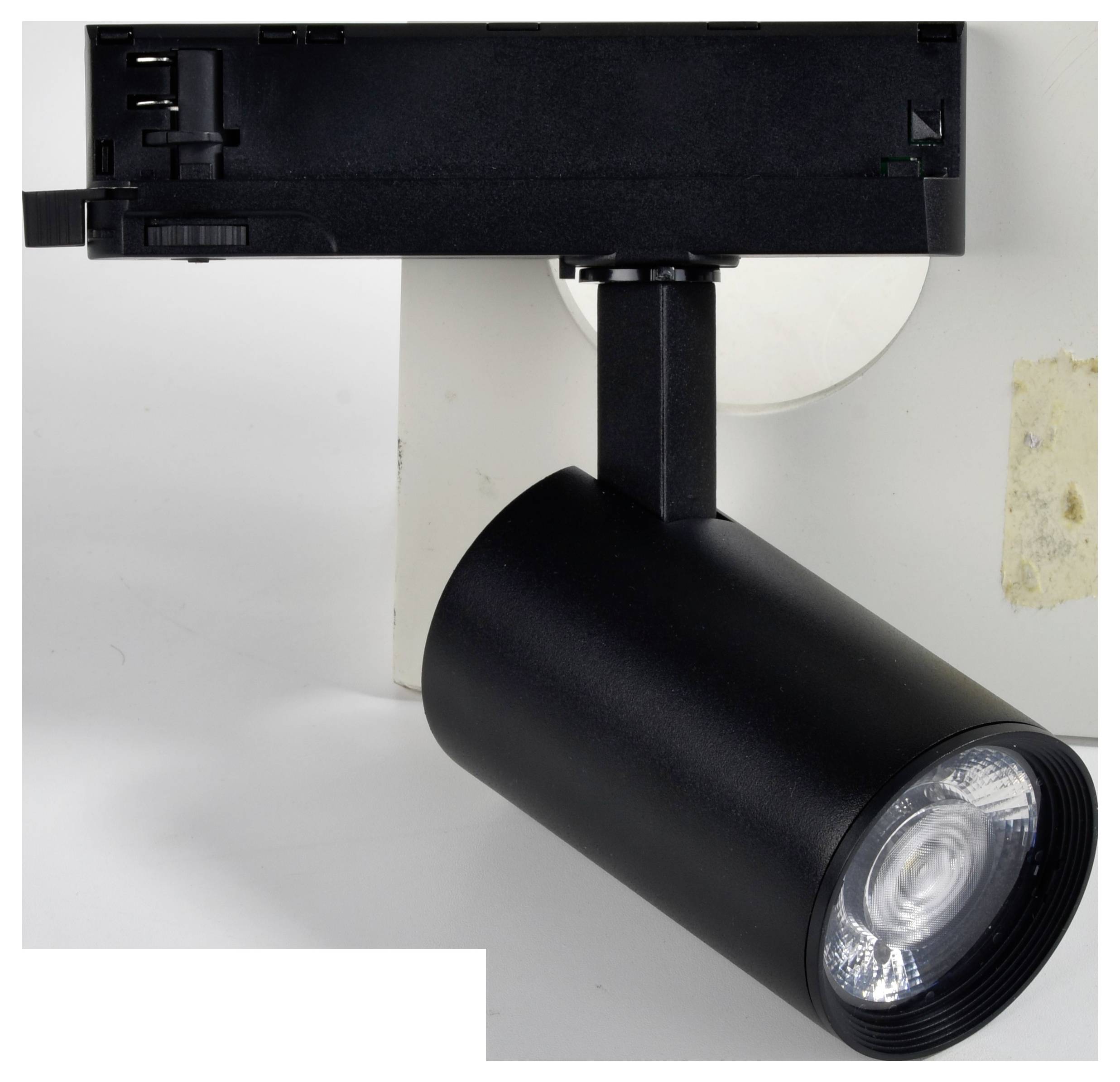 Čierna valcovitá stropná lampa s otočnou hlavicou upevnená na obdĺžnikovej koľajnicovej základni, postávajúca pred jednoduchým pozadím.