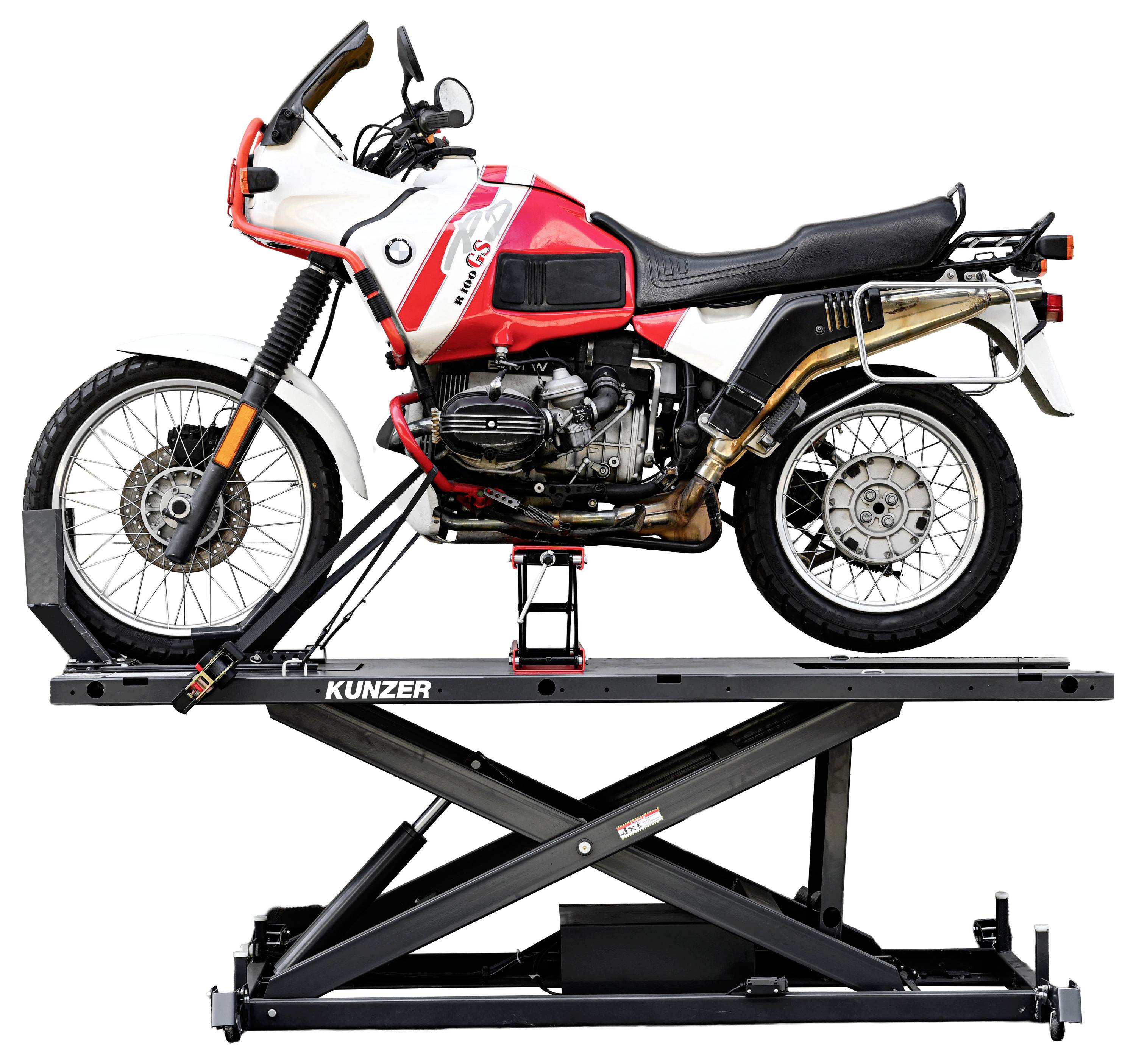Červeno-biela motorka je umiestnená na zdvihnutej hydraulickej plošine, ktorá zobrazuje jej bočný pohľad.