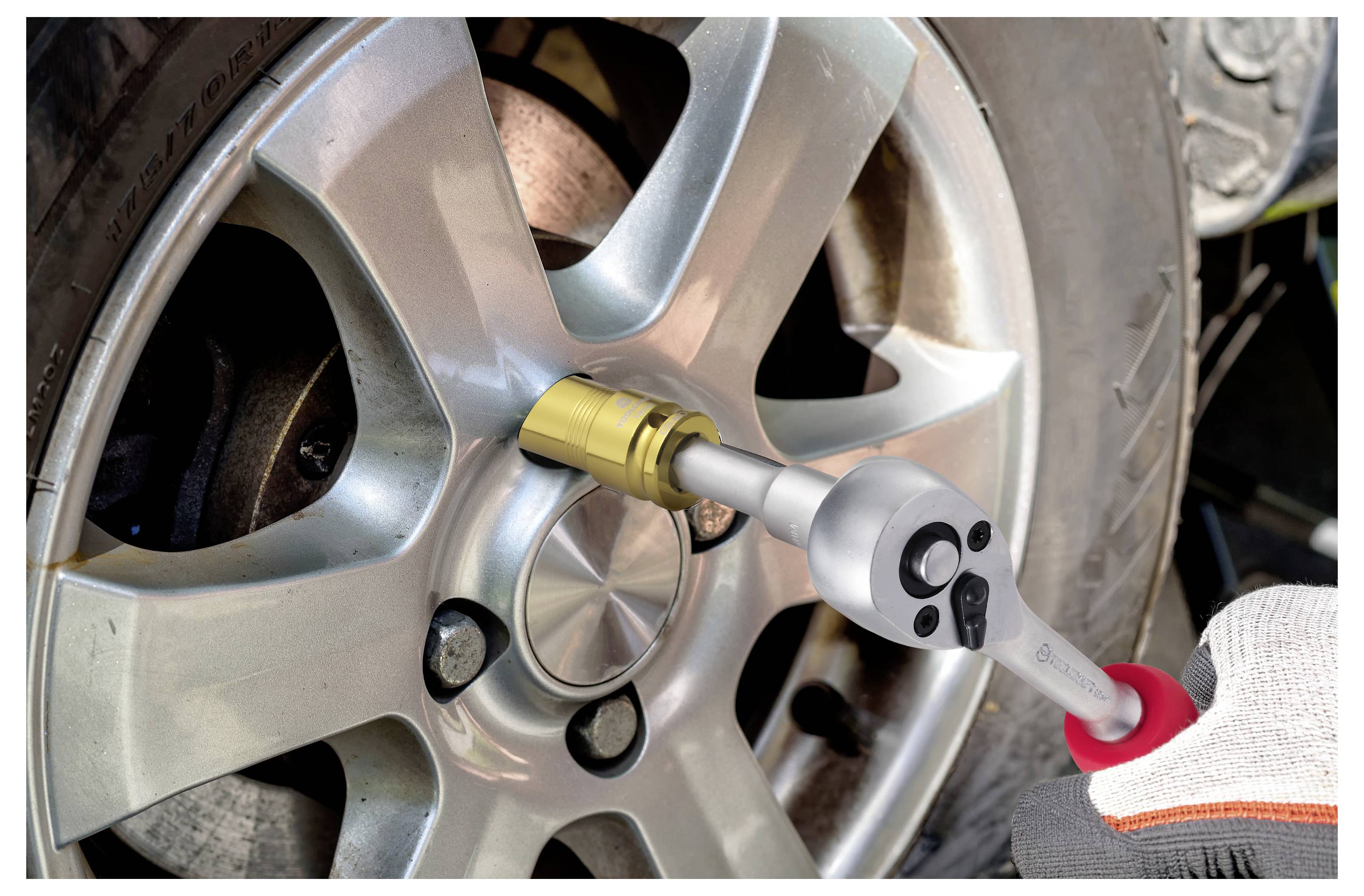 Mechanik používa momentový kľúč na utiahnutie matice na kolesе automobilu, čo znázorňuje údržbu vozidla.