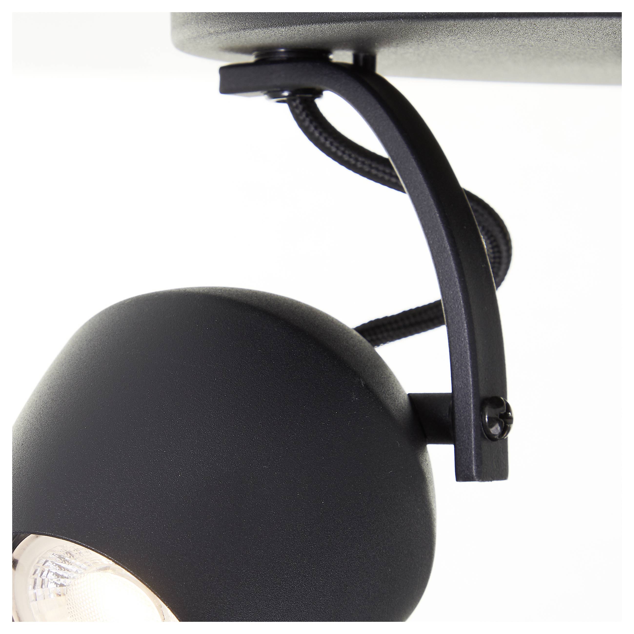 Detailný záber moderného čierneho stropného svietidla s oblúkovitým ramenom a pripojeným elektrickým vedením.