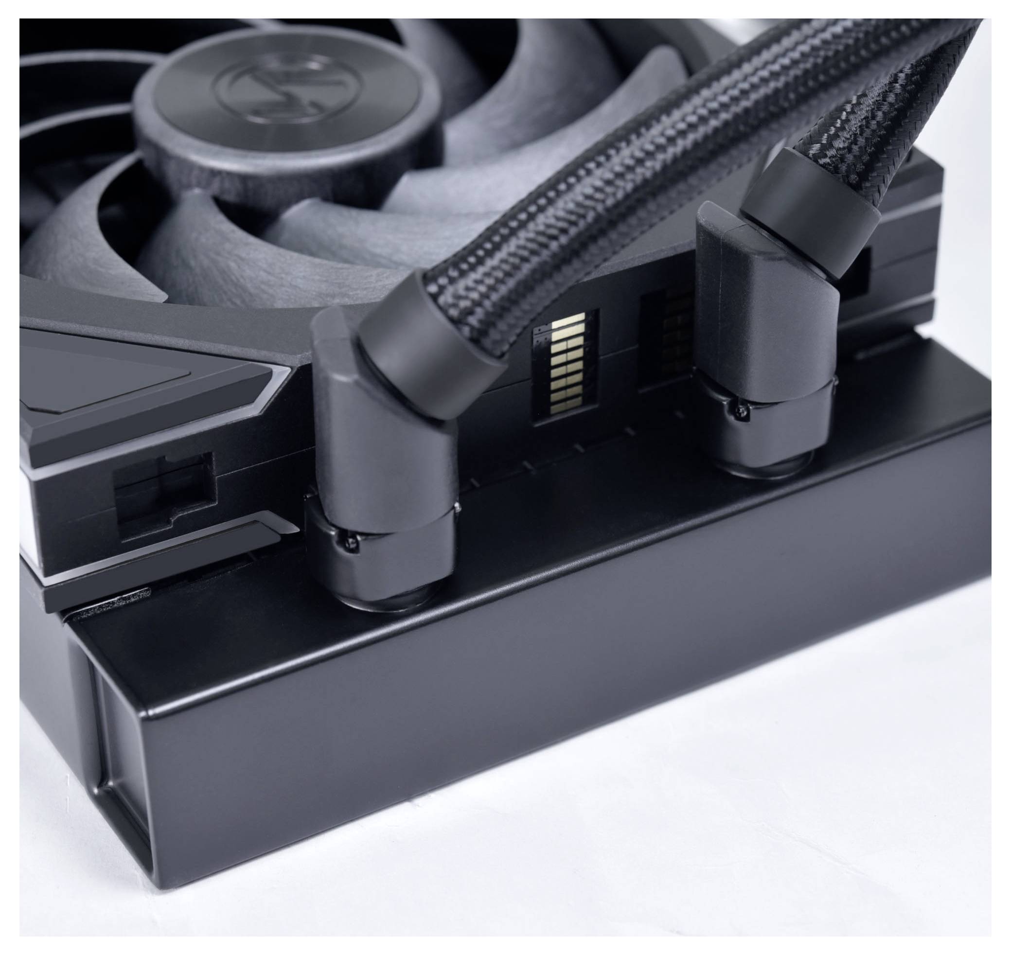 Detailný záber počítačového chladiaceho systému zobrazujúci ventilátor a dve pletené hadičky pripojené k čiernej chladiaci jednotke.