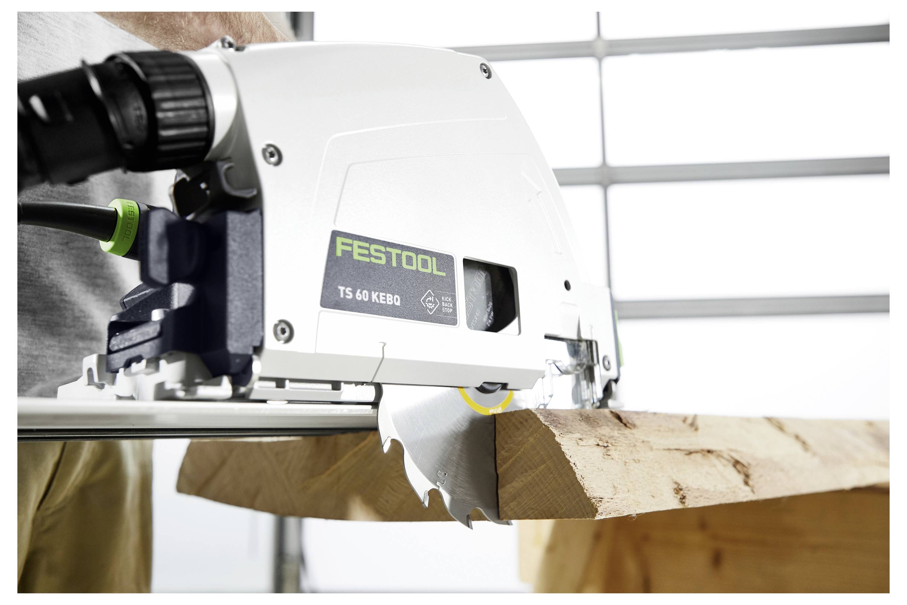 Okružná píla označená "Festool TS 60 KEBQ" reže cez drevenú dosku, čím ilustruje presnosť v nástrojoch na spracovanie dreva.