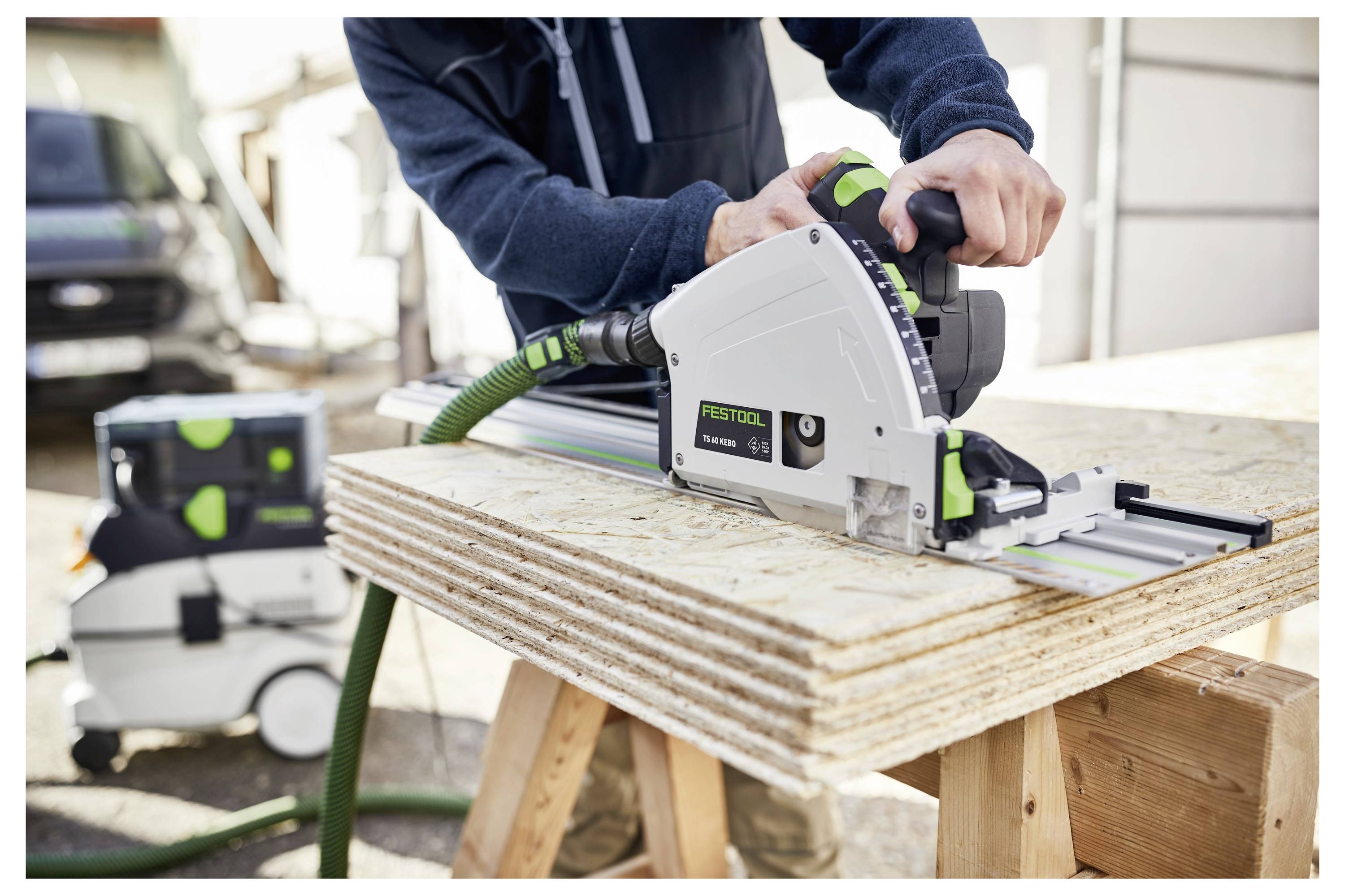 Osoba používajúca okružnú pilu na rezanie naskladaného preglejovaného dreva vonku.