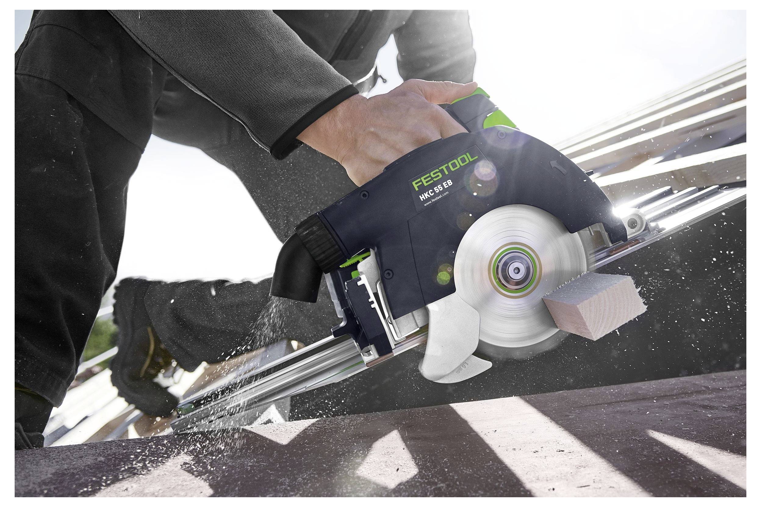 Osoba používa okružnú pílu na rezanie dreva na stavenisku, pričom scénu osvetľuje slnečné svetlo a vzniká piliny.