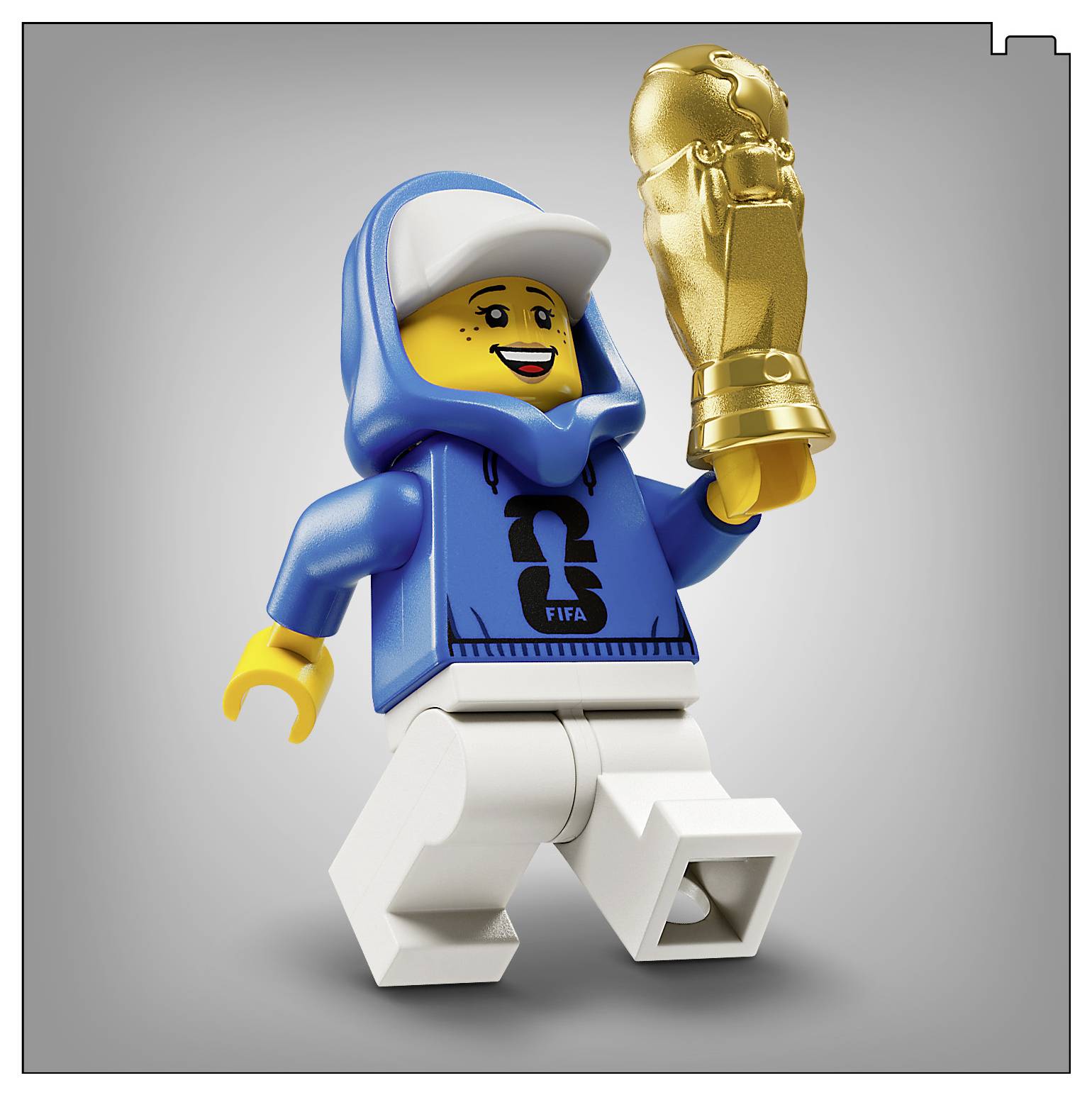 Figurka LEGO v modrom kabáte s kapucňou a bielych nohaviciach drží zlatý pohár a žiari jasným úsmevom na neutrálnom pozadí.