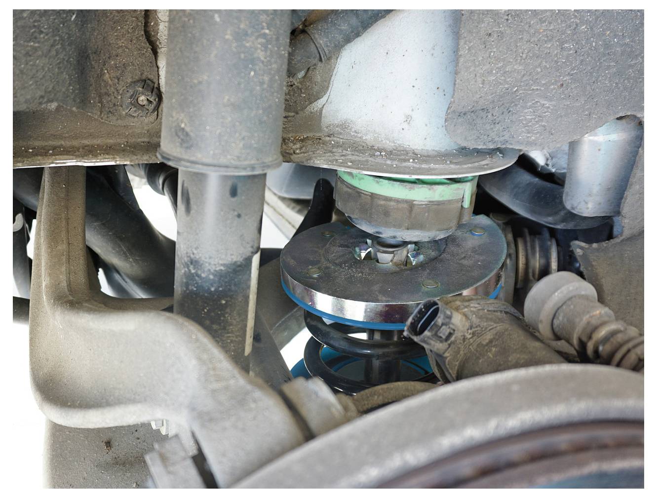 Zblízka pohľad na zavesenie automobilu, zobrazujúce rôzne komponenty vrátane pružín a tlmičov, zdôrazňujúce mechanické detaily.