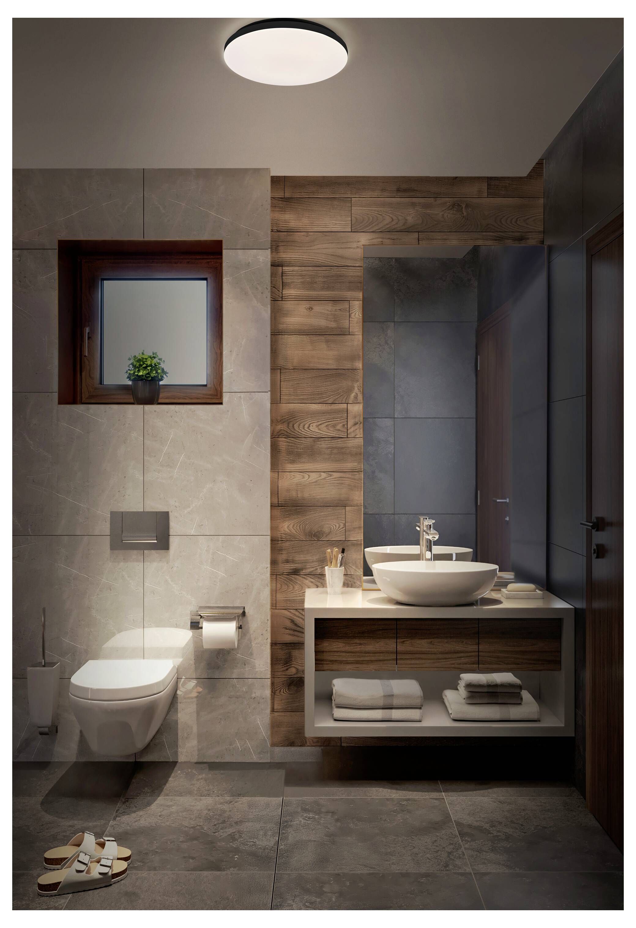 Moderná kúpeľňa so závesným WC, okrúhlym umývadlom na pracovnej doske, uterákmi, toaletným potrebami a drevennými prvkami pod mäkkým osvetlením.