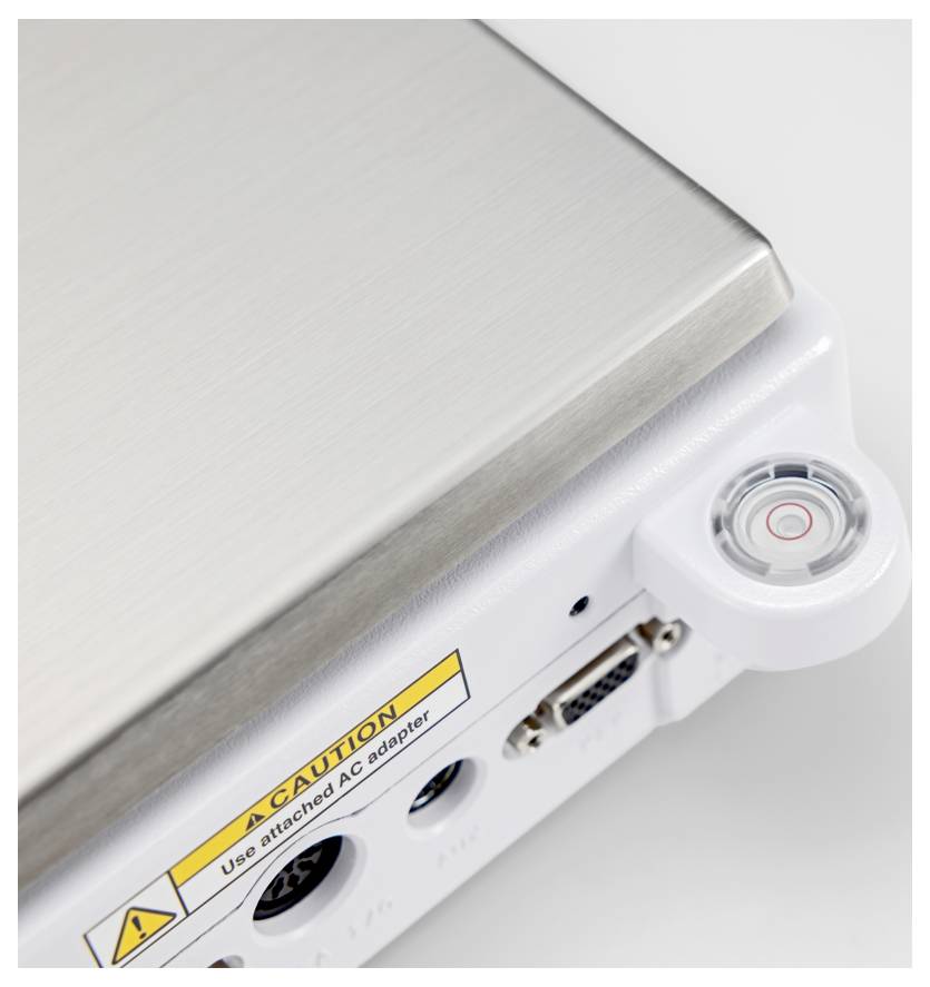 Strieborné elektronické zariadenie so zblížením na tlačidlo napájania a upozornením: „Používajte priložený adaptér AC." Vrátane portov USB a VGA.
