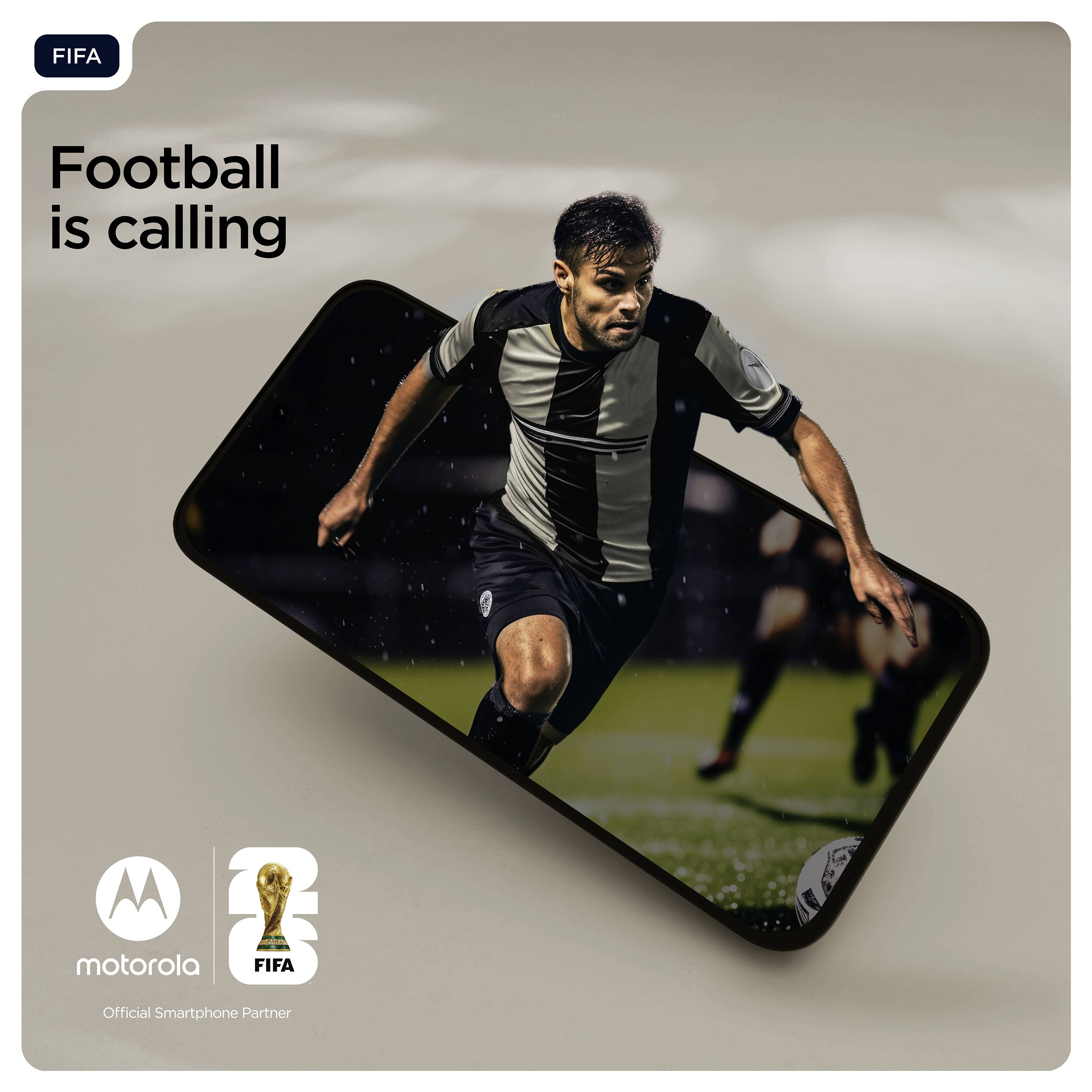 Futbalista v čiernobielom drese beží na ihrisku, pričom je v popredí viditeľná obrazovka smartfónu.