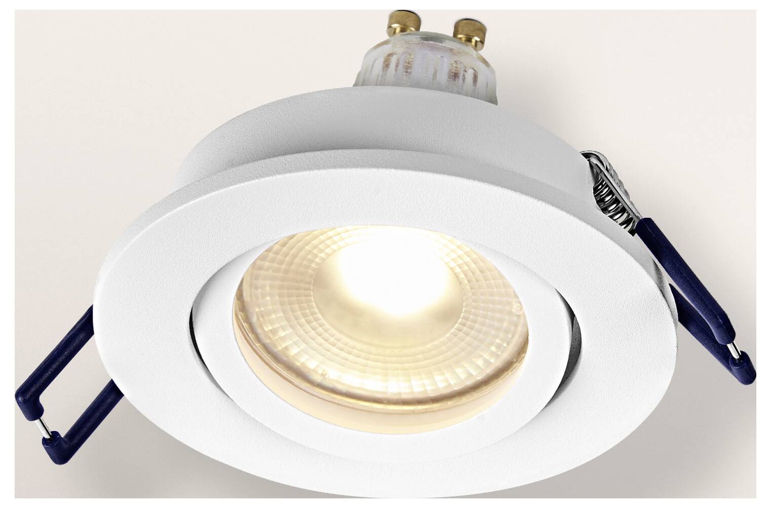 Biela zapustená svetelná armatúra so svietiacou žiarovkou, pripevnená na strope, s viditeľnými kovovými svorkami na inštaláciu.