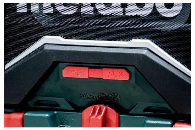 Zblízka zobrazená krabica s nástrojmi označená 'metaBOX' s červeným tlačidlom 'AUX' a symbolom USB nad ním.