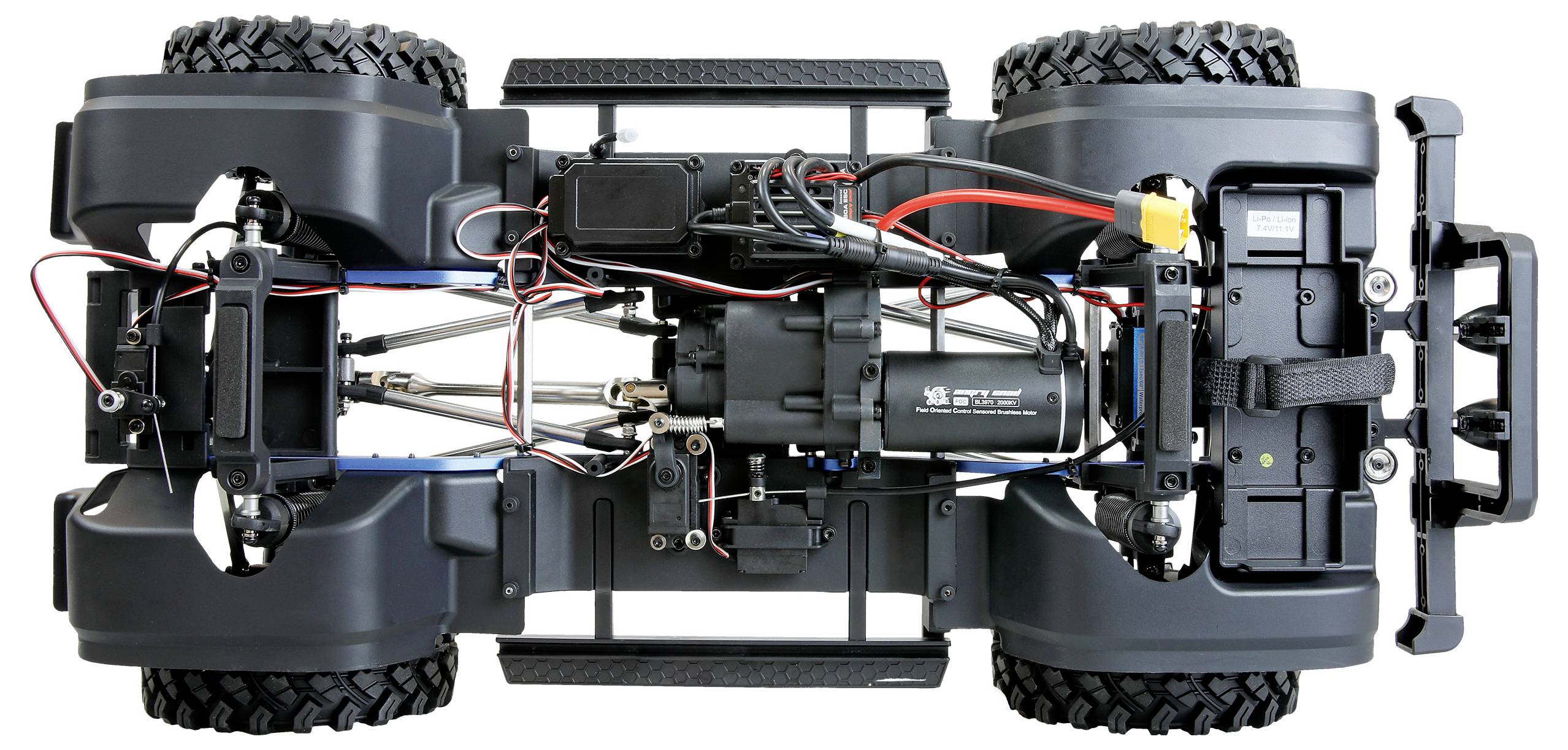 Pohľad na spodnú stranu podvozku diaľkovo ovládaného terénneho vozidla, zobrazujúci štyri veľké pneumatiky, odpruženie, motor, batériu a elektrické vedenie.