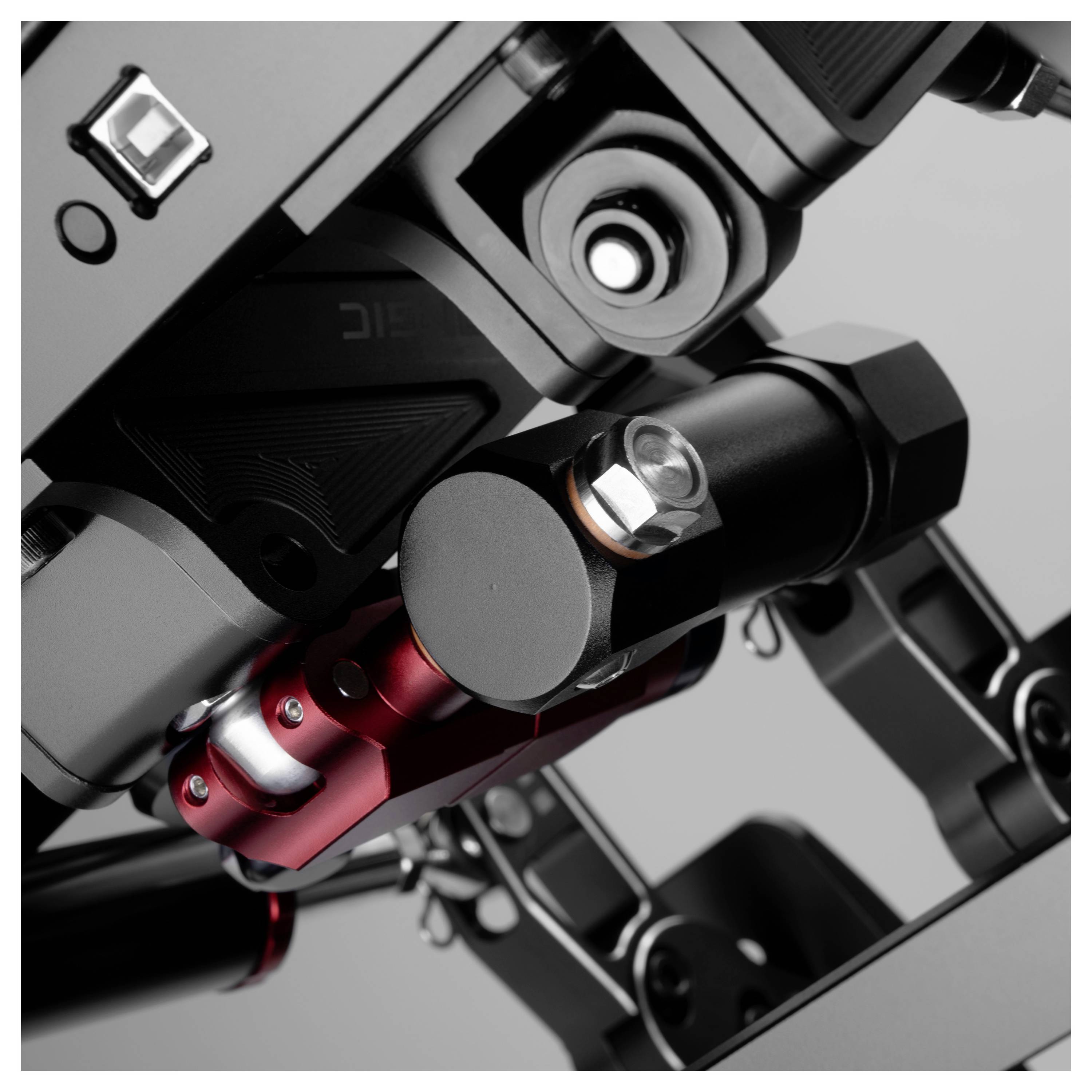 Zväčšený pohľad na mechanickú robotickú rameno alebo kamera gimbal s čiernymi, červenými a strieborným spojmi a upevňovačmi na sivom pozadí.
