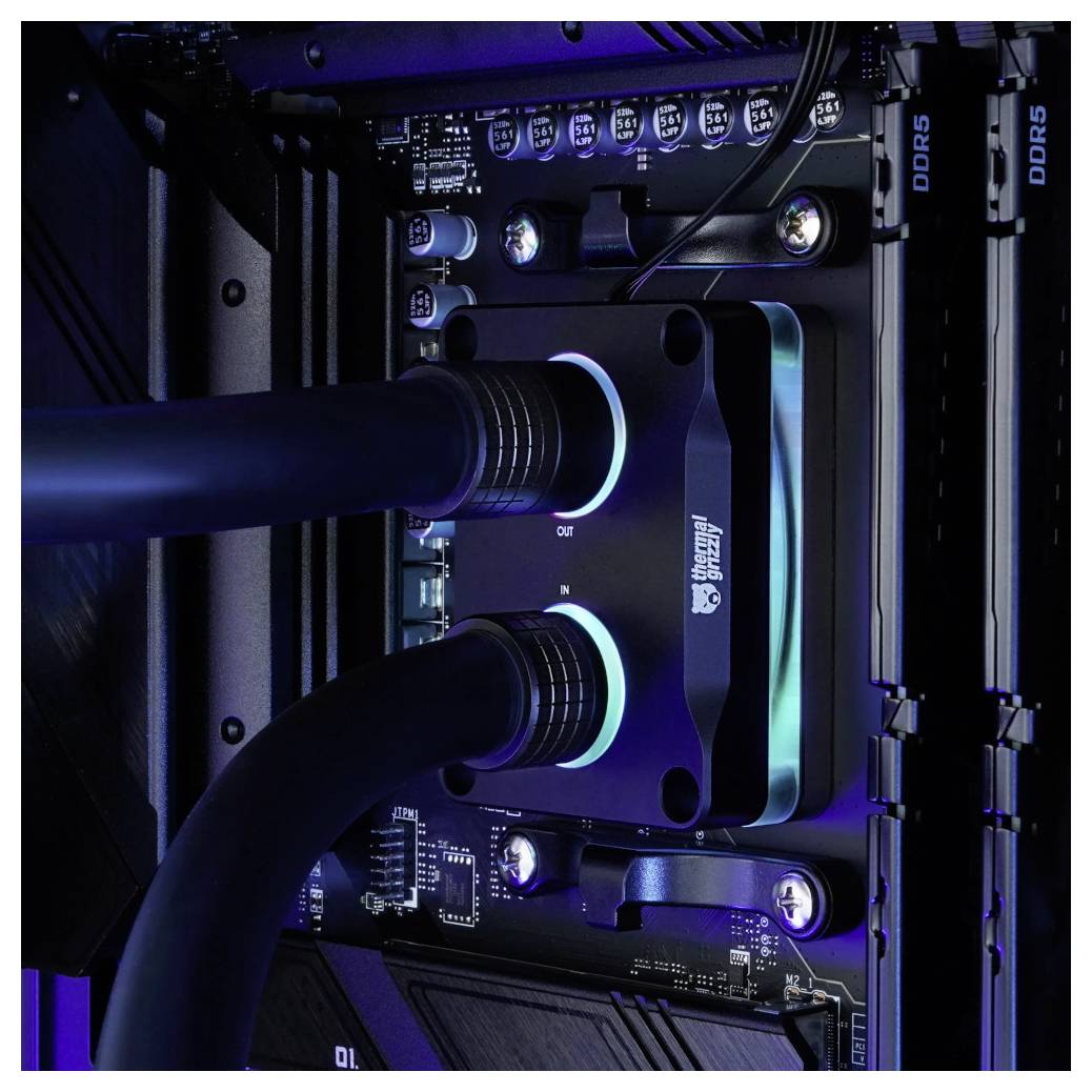 Zblízka pohľad na vlastný PC motherboard s kvapalinným chladičom CPU a dvomi chladiacimi hadičkami, popri DDR5 RAM moduloch a modrým LED osvetlením.