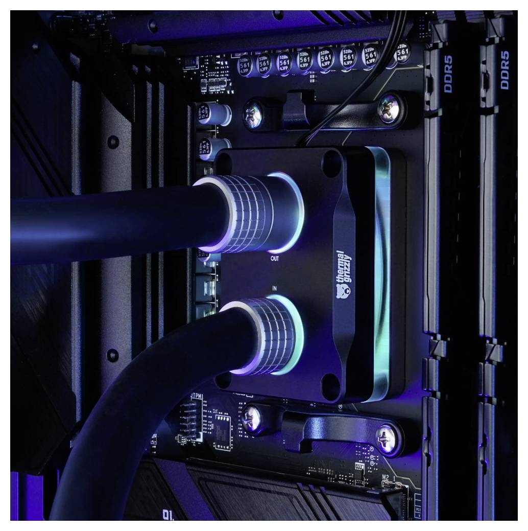 Detailný pohľad na chladený kvapalinou desktop PC matičnú dosku, zobrazujúci blok chladenia procesora s dvoma hadičkami chladiacim prostriedkom a RAM modulmi označenými ako DDR5.