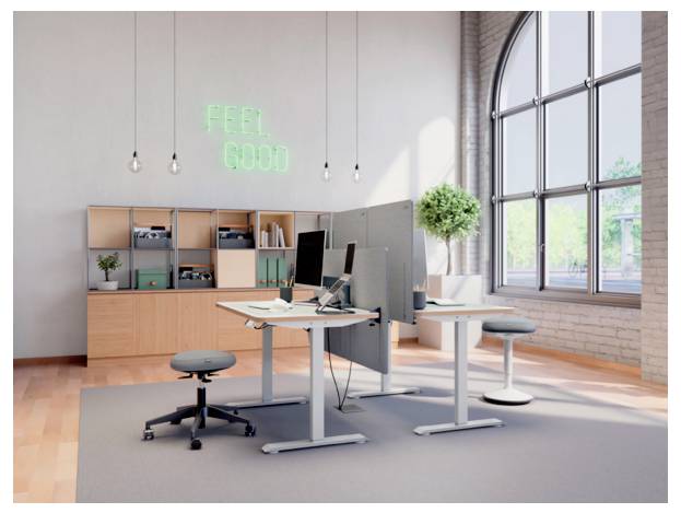 Moderná open office s állacími stolmi, počítačovými monitormi, policami, stolčekmi, veľkým oknom a neónovým nápisom "FEEL GOOD" na stene.