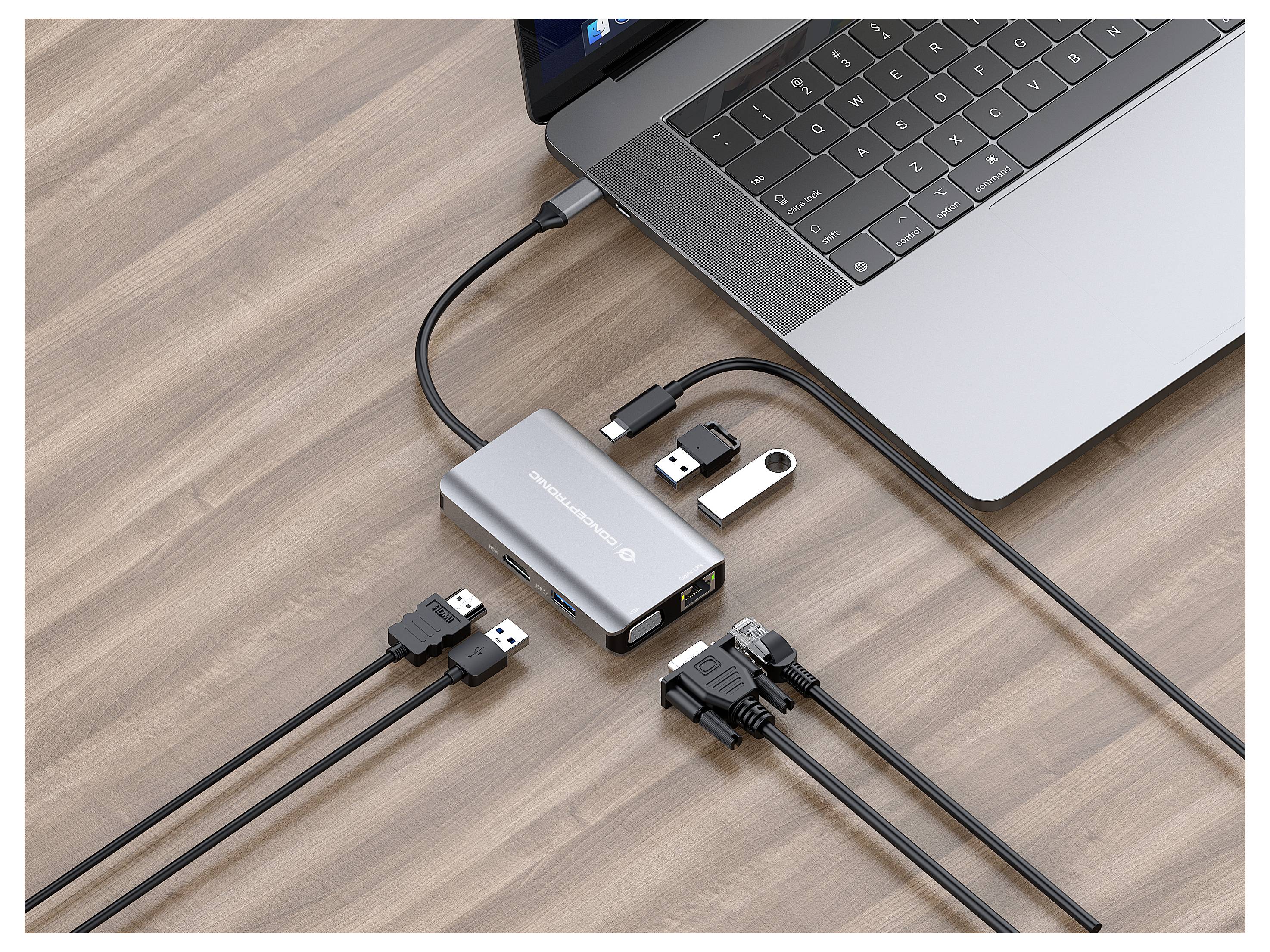 Notebook pripojený k USB hubru/dokovacej stanici na stole s viacerými USB kábľami a flash diskom zapnutým.
