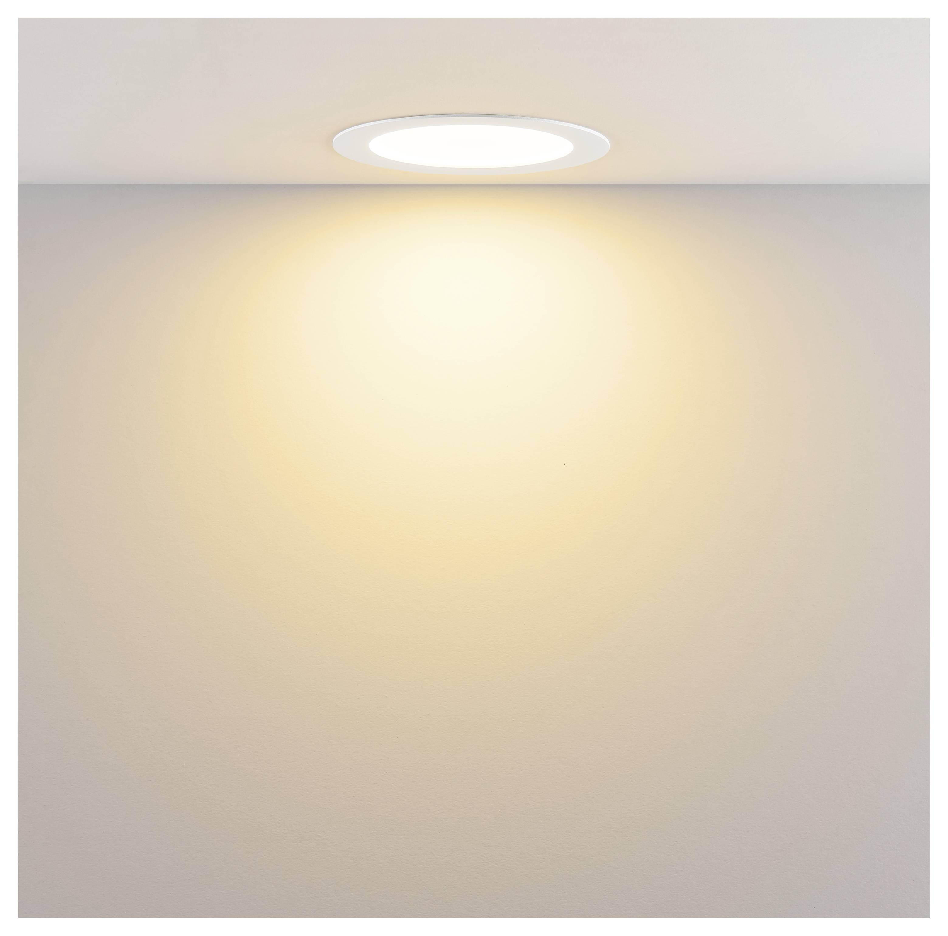 Stropne zabudovaný okrúhly zapustený svetelný zdroj vrhajúci teplé svetlo na jednoduchú stenu.