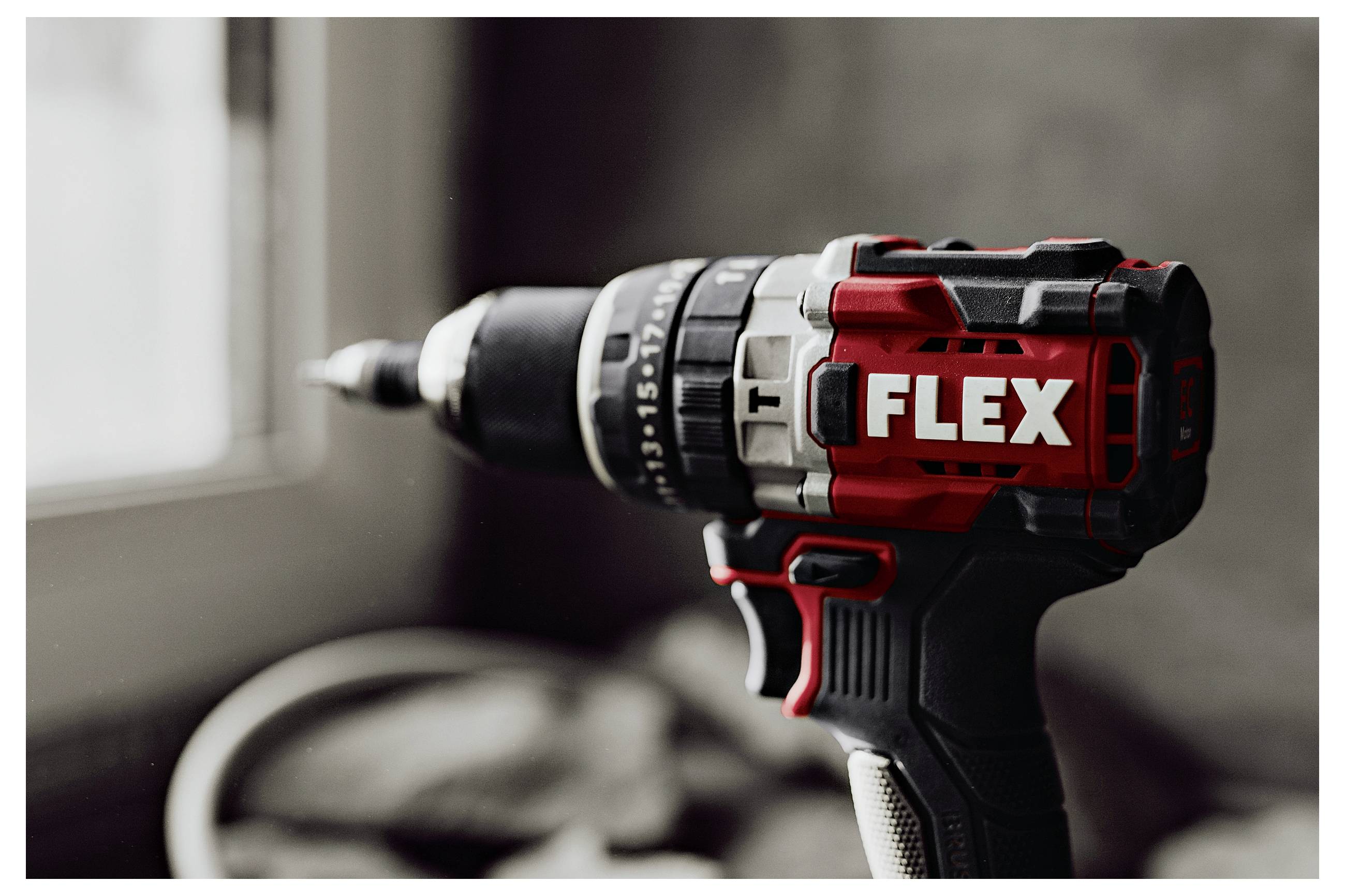 Bezdrôtová vŕtačka/skrutkovač FLEX s nasadeným bitom, zobrazená v detailnom zábere pri okne.