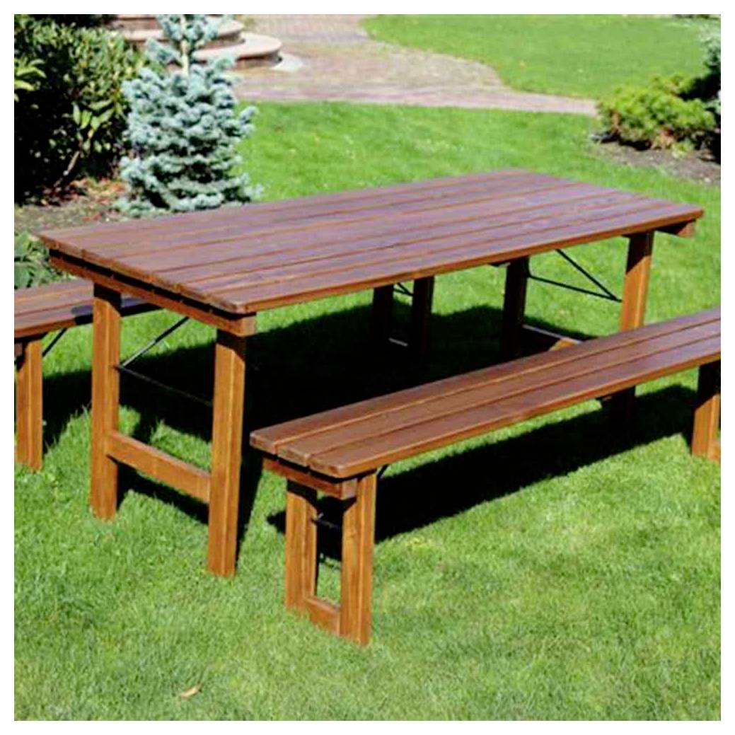 Drevený vonkajší piknikový stôl s pripevnenými lavičkami na trávnatom trávniku v záhrade.