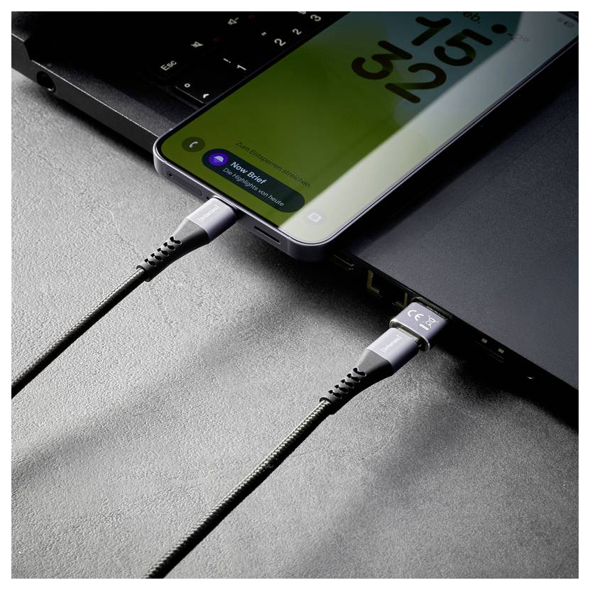 Smartfón a notebook sú prepojené nabijacími kábľami, pričom telefón sa nabíja počas pripojenia k notebooku.