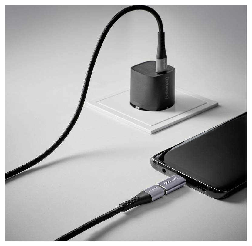 USB-C kábel zapojený do smartfónu vedľa kompaktnej dokovacej stanice na bielom povrchu.
