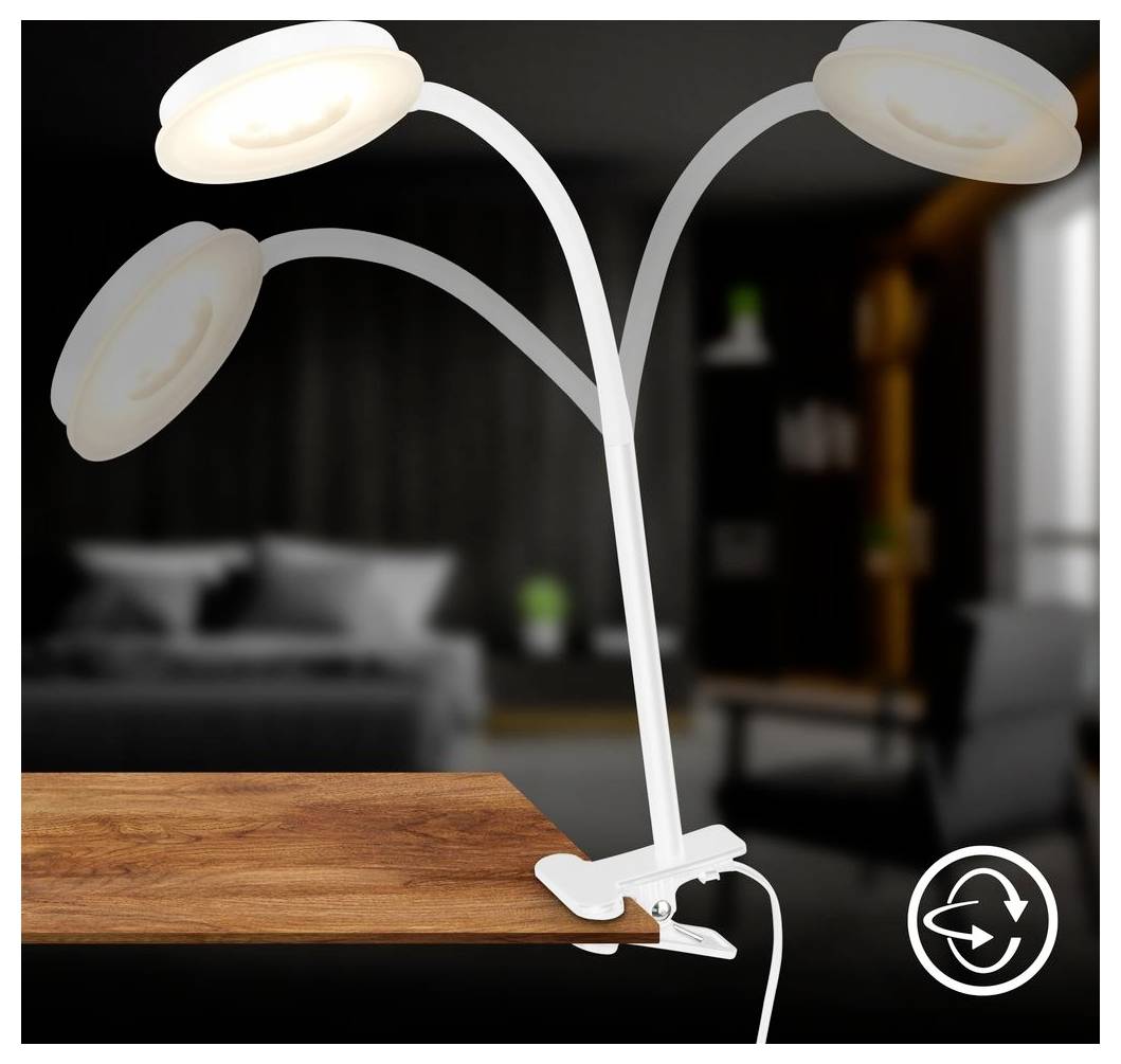 Biela klipsová stolná lampa s tromi nastaviteľnými LED hlavicami pripevnenými na dreveného stola v modernej miestnosti, so ikonou dotykovej kontroly zobrazenou v pravom dolnom rohu.